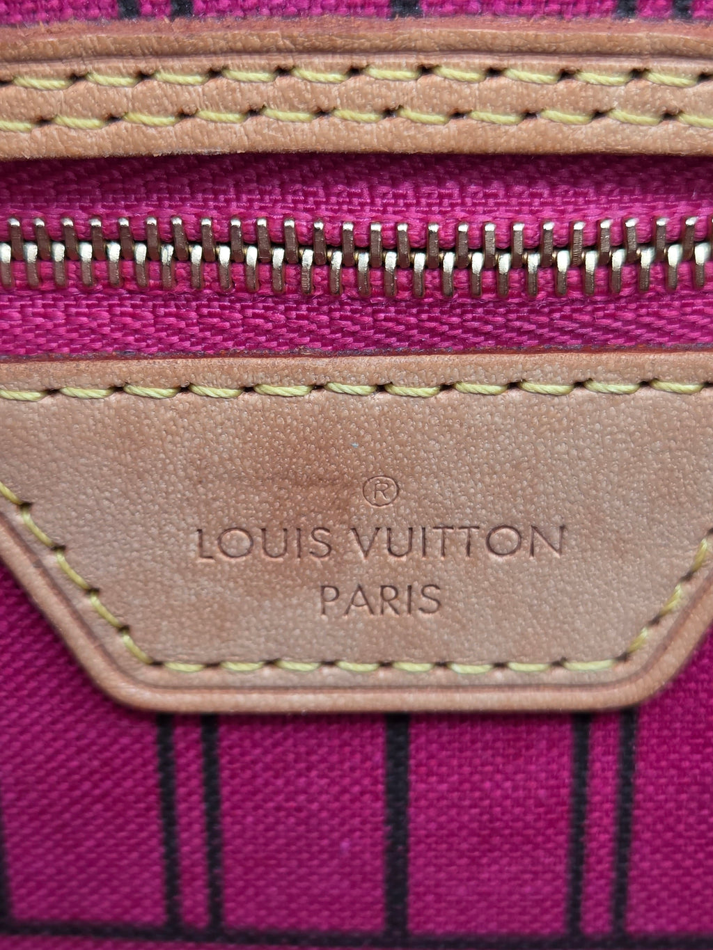 Close-up of a Louis Vuitton suitcase with pink and black striped pattern
