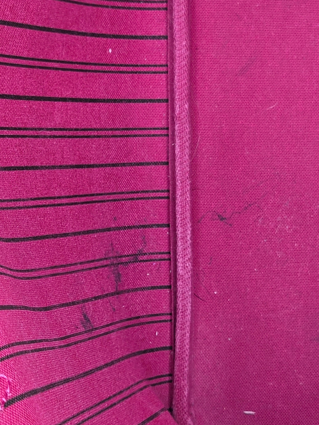 Close-up of a pink fabric with black vertical stripes and visible stitching.