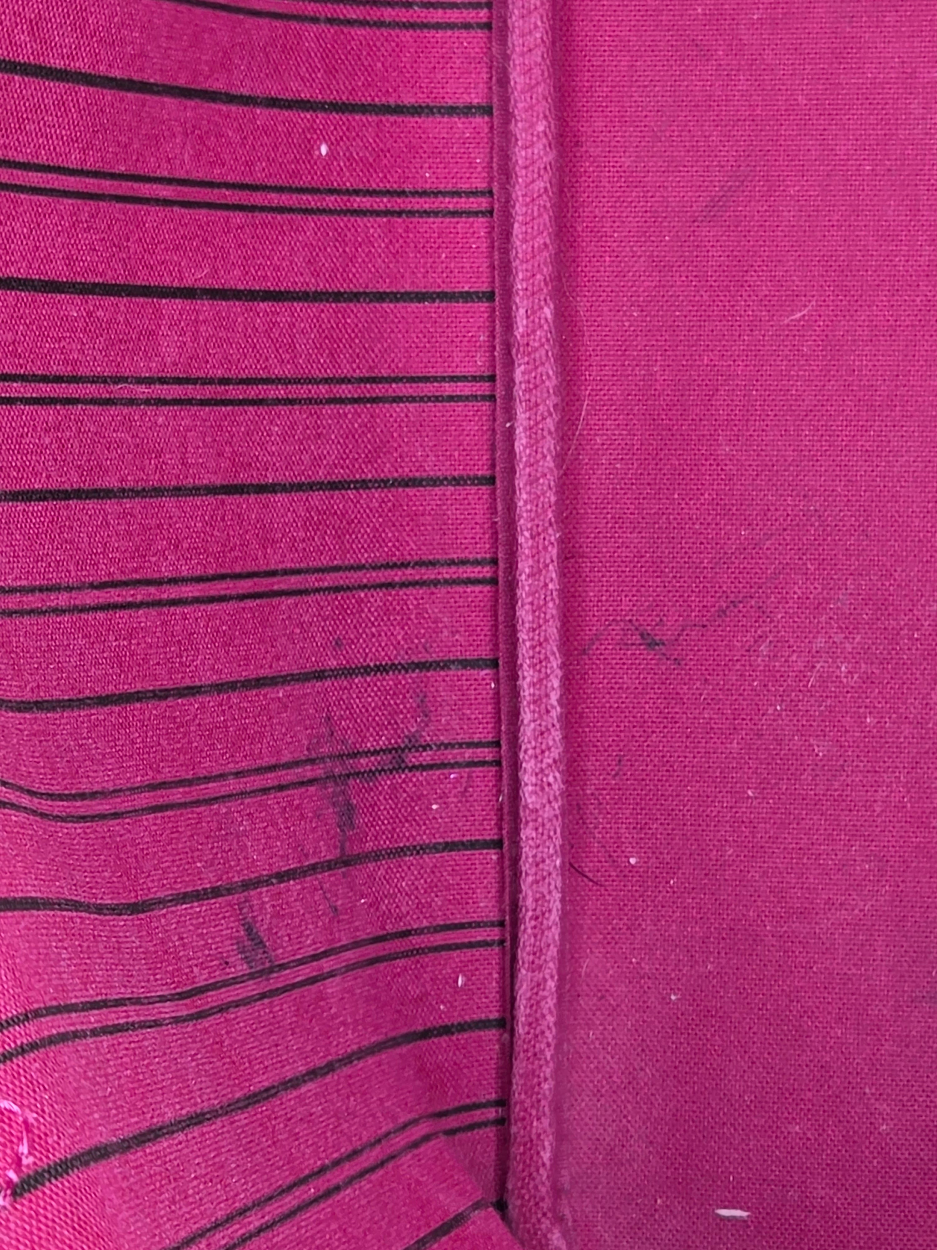 Close-up of a pink fabric with black vertical stripes and visible stitching.