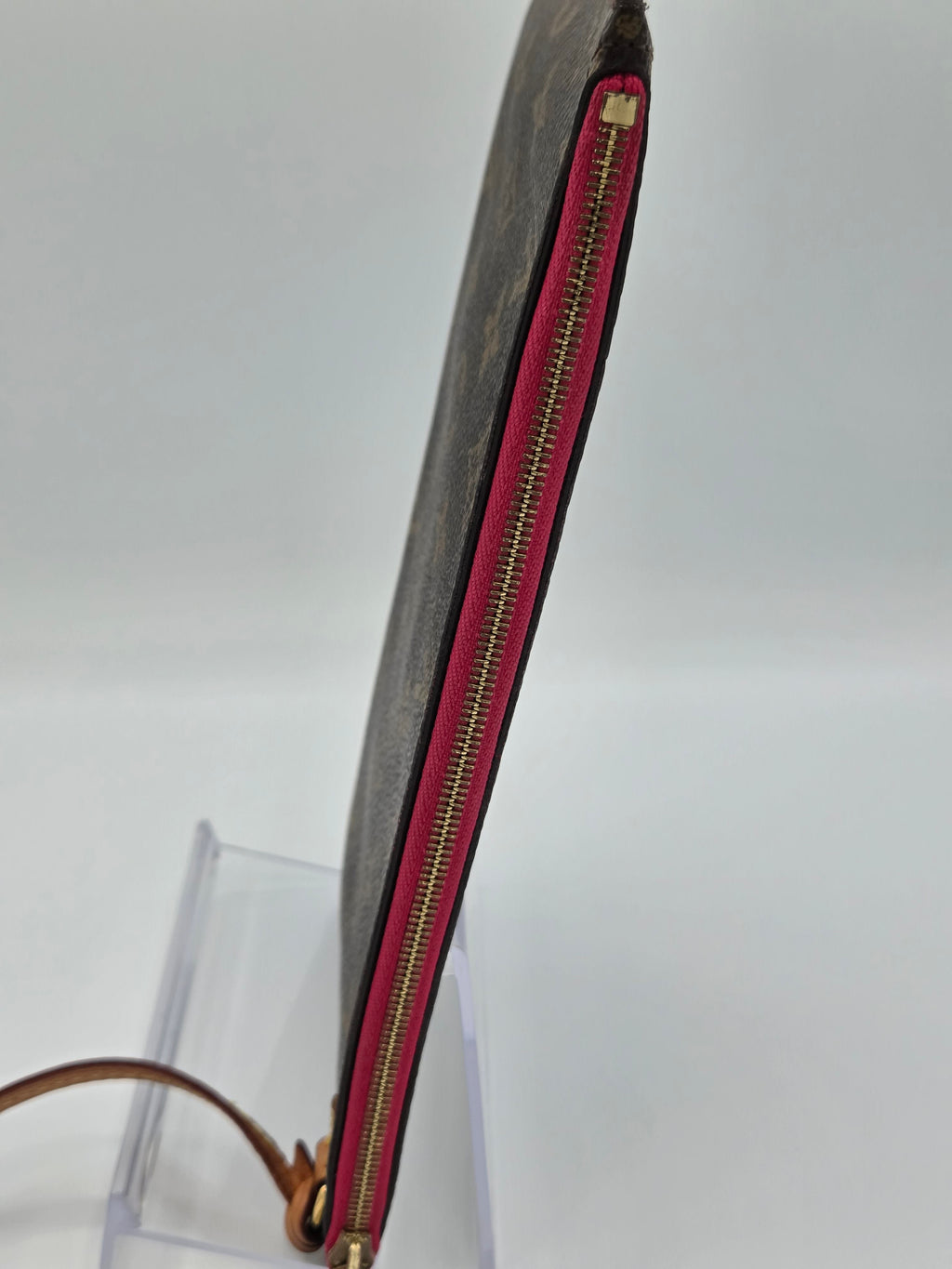 Long rectangular pouch with red zipper on a clear stand against a white background