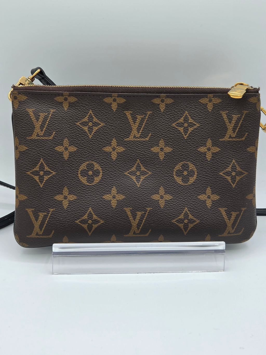 Louis Vuitton monogram handbag on a stand against a white background