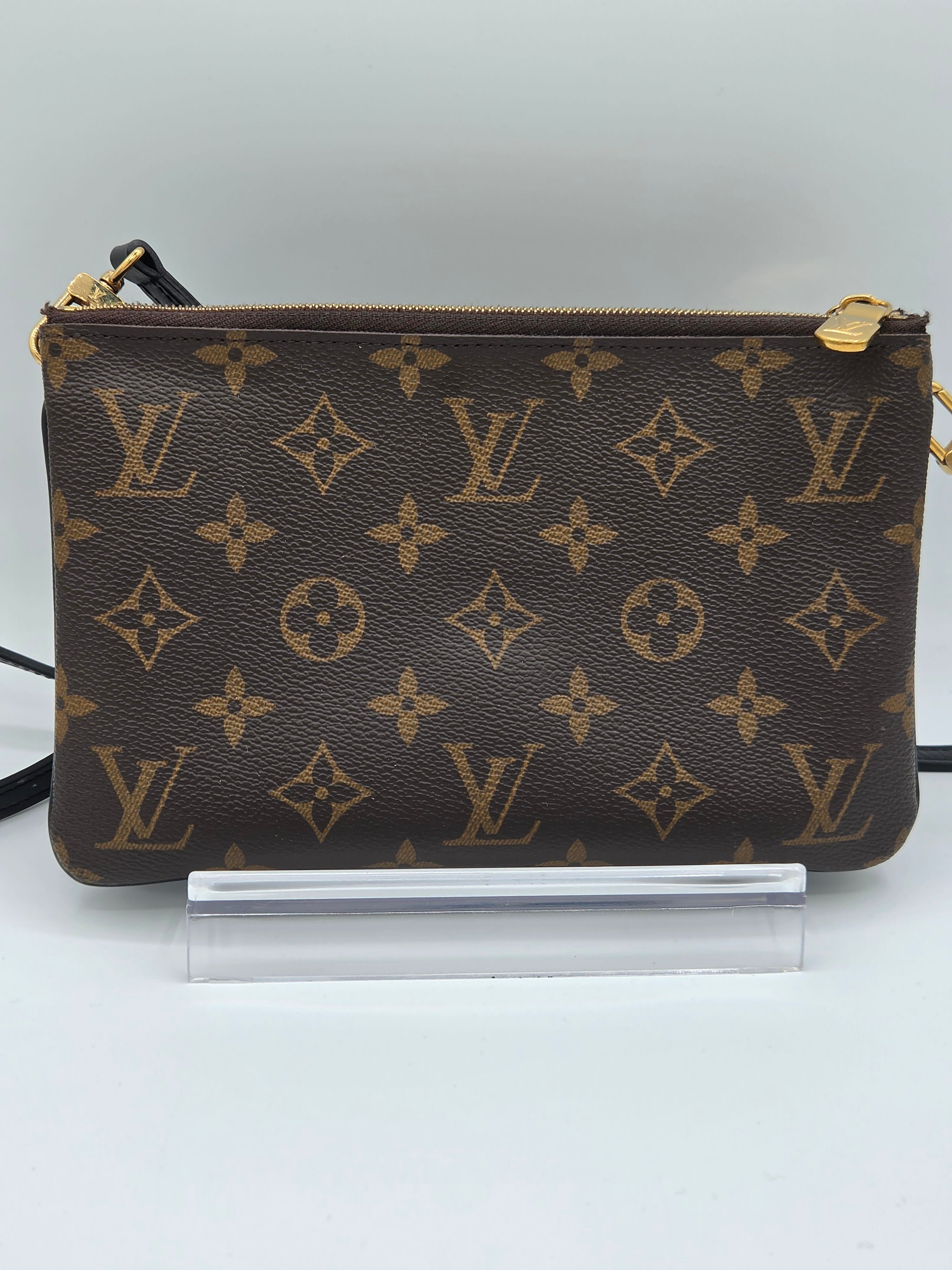 Louis Vuitton monogram handbag on a stand against a white background