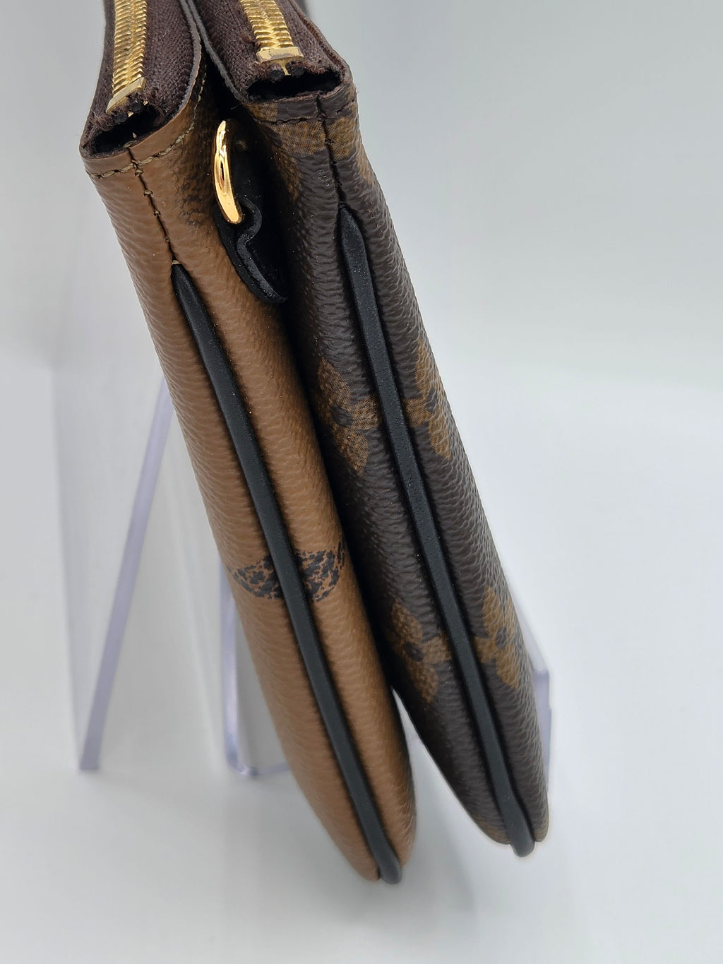 Folded brown leather wallet with gold accents on a light gray background
