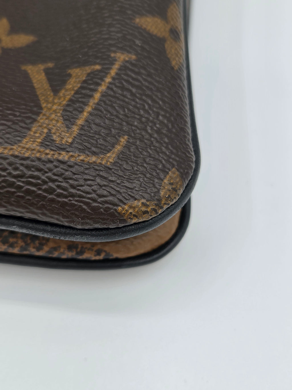 Close-up of a Louis Vuitton wallet with monogram pattern on a white background