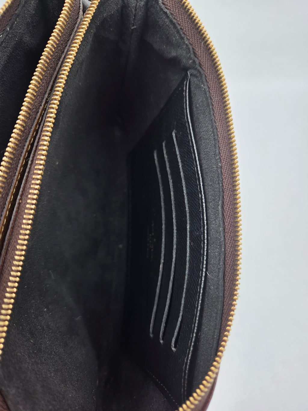 Close-up of a black leather bag with gold zipper on a gray background
