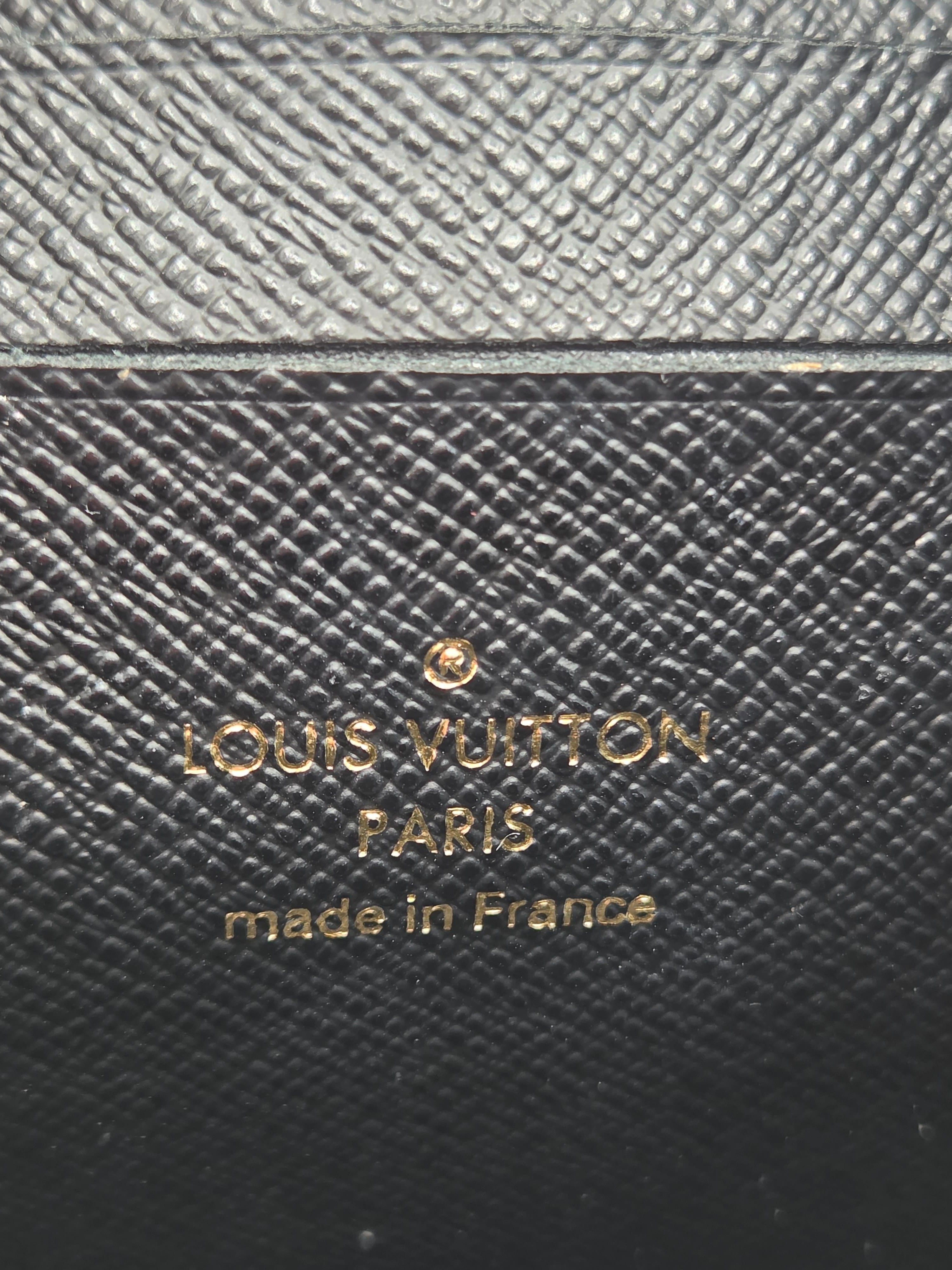 Louis Vuitton wallet with brand name and 'made in France' text on textured leather surface