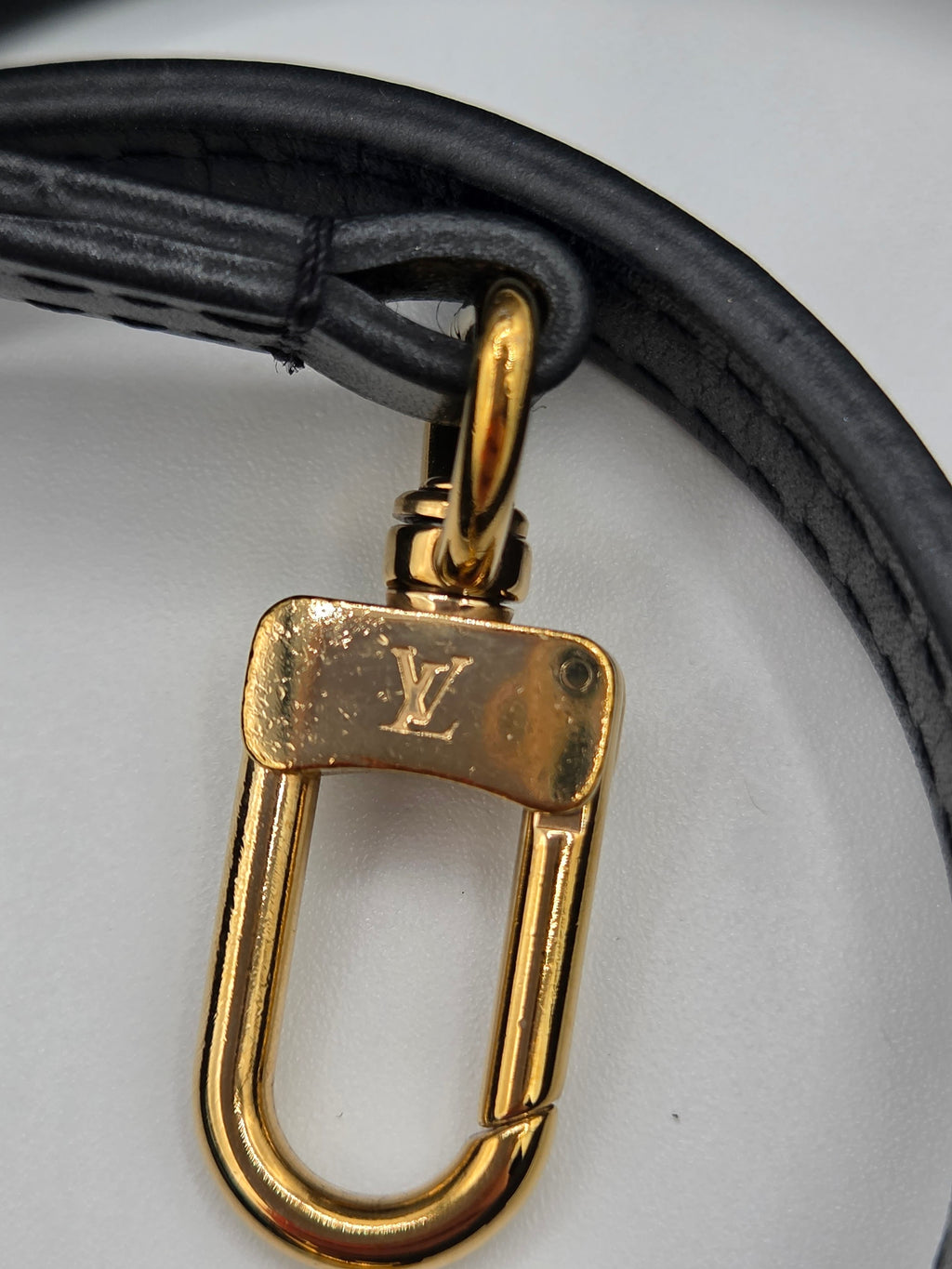 Gold carabiner with a black cord on a white background