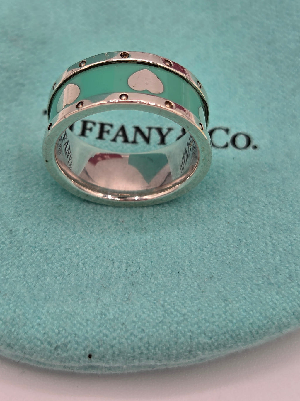 Two Tiffany & Co. rings on a green cushion with the brand's logo.