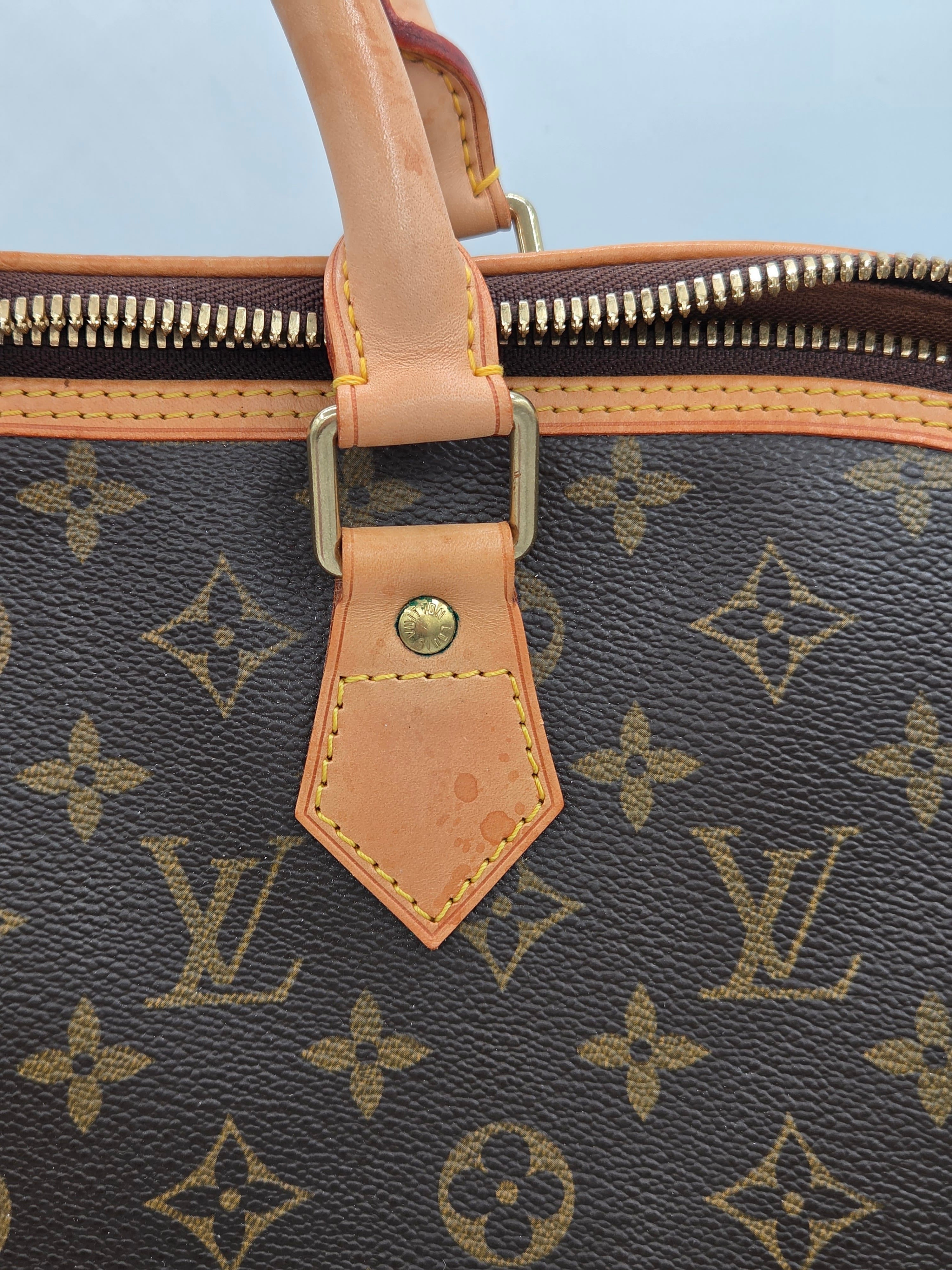 Close-up of a Louis Vuitton handbag with monogram pattern and beige handle.