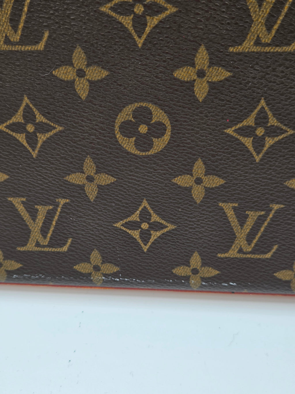 Close-up of a brown leather surface with gold Louis Vuitton monogram pattern.