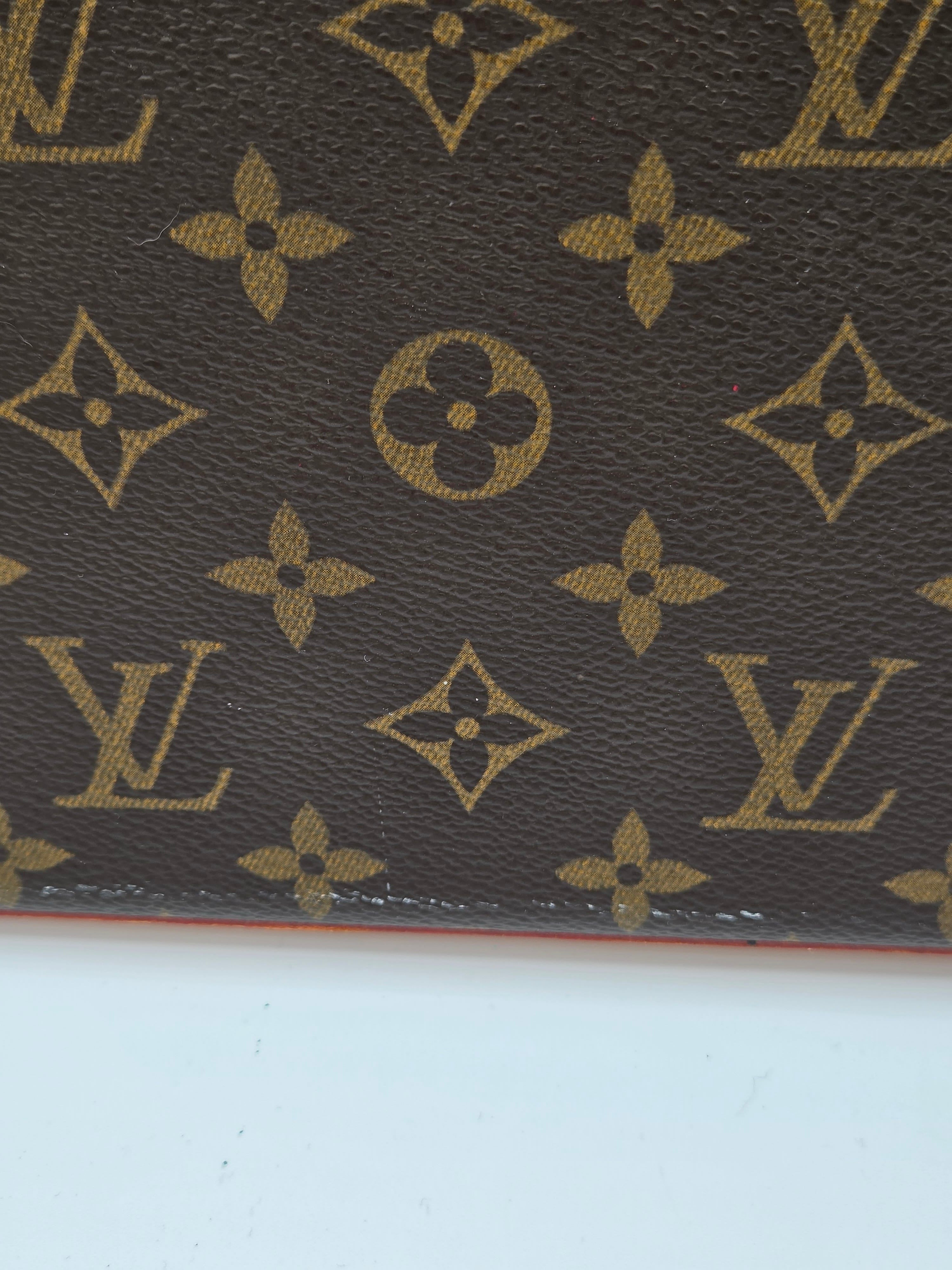 Close-up of a brown leather surface with gold Louis Vuitton monogram pattern.