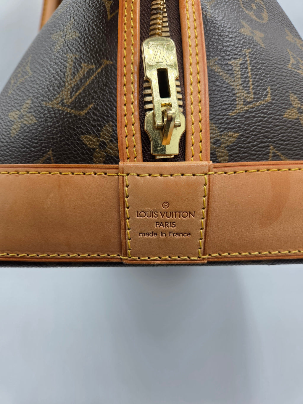 Close-up of a Louis Vuitton handbag with monogram pattern and gold zipper.