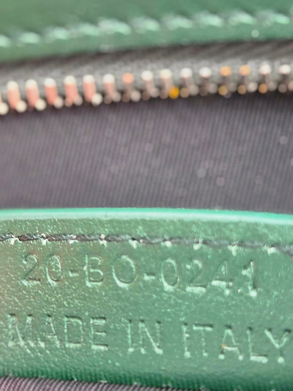 Close-up of a green leather label on a black bag with 'Made in Italy' text.