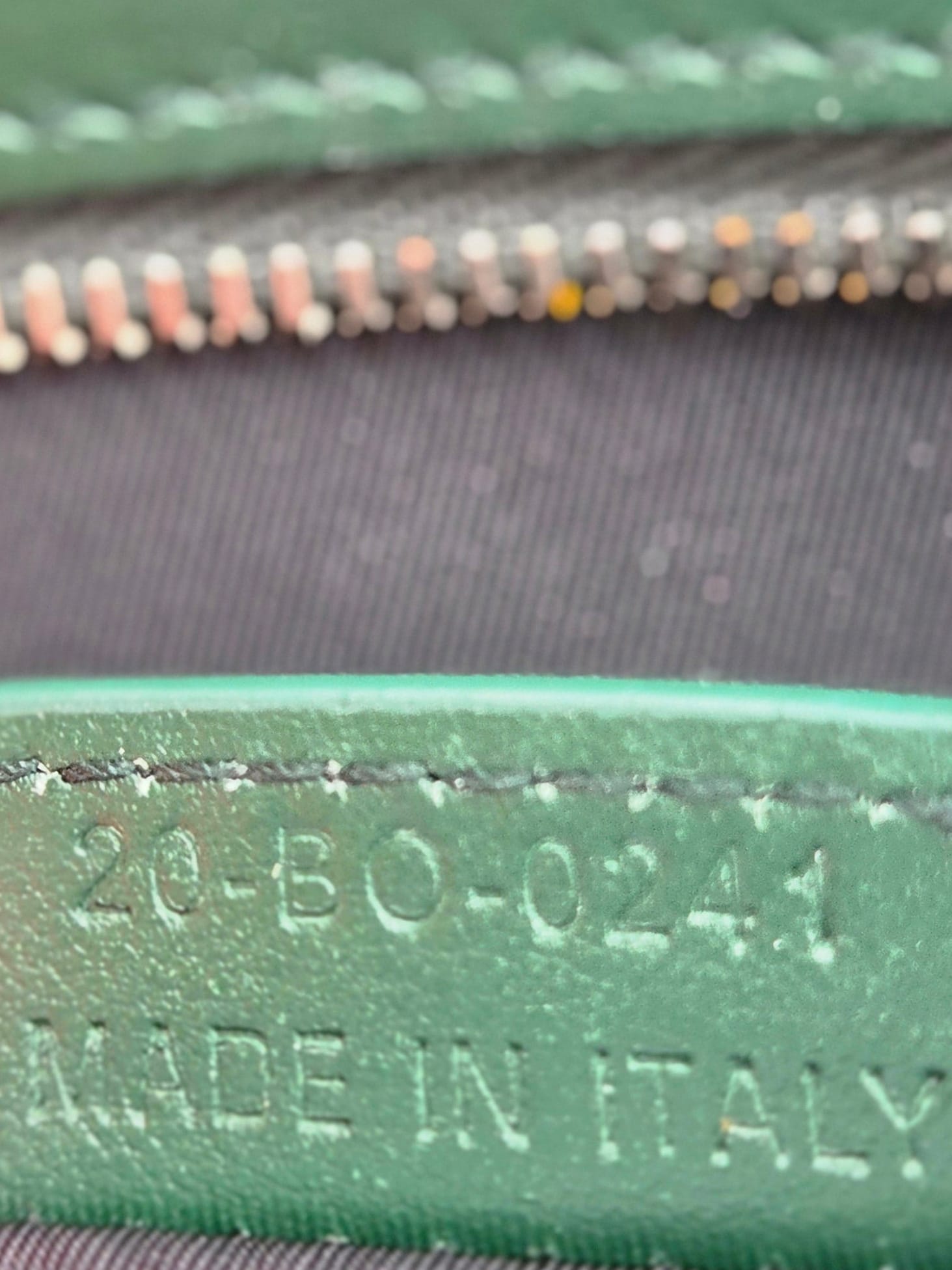 Close-up of a green leather label on a black bag with 'Made in Italy' text.