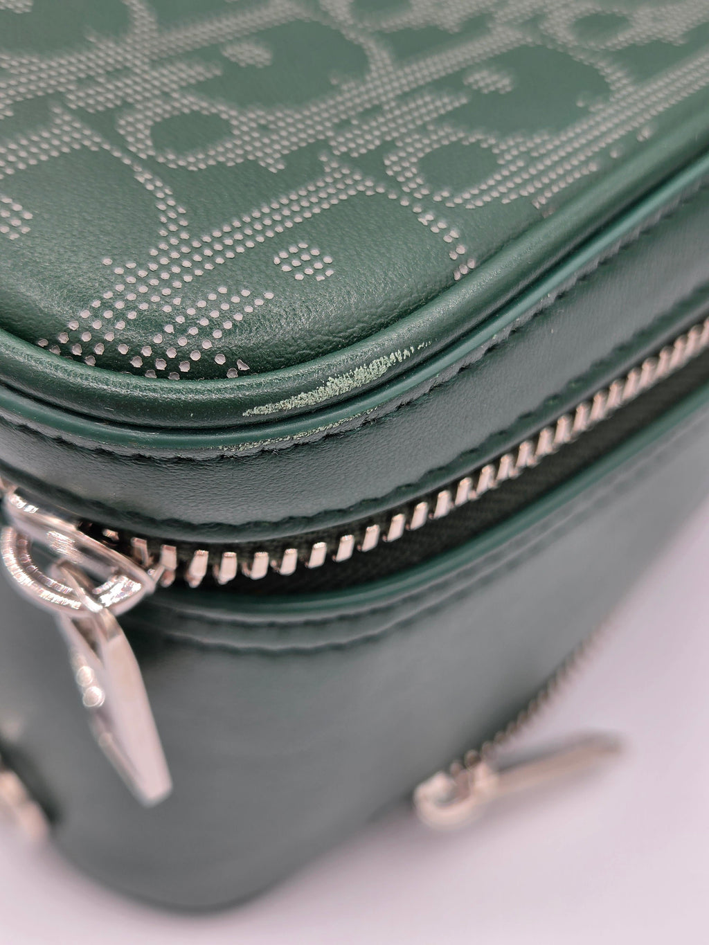 Green textured handbag with a silver zipper on a light gray background