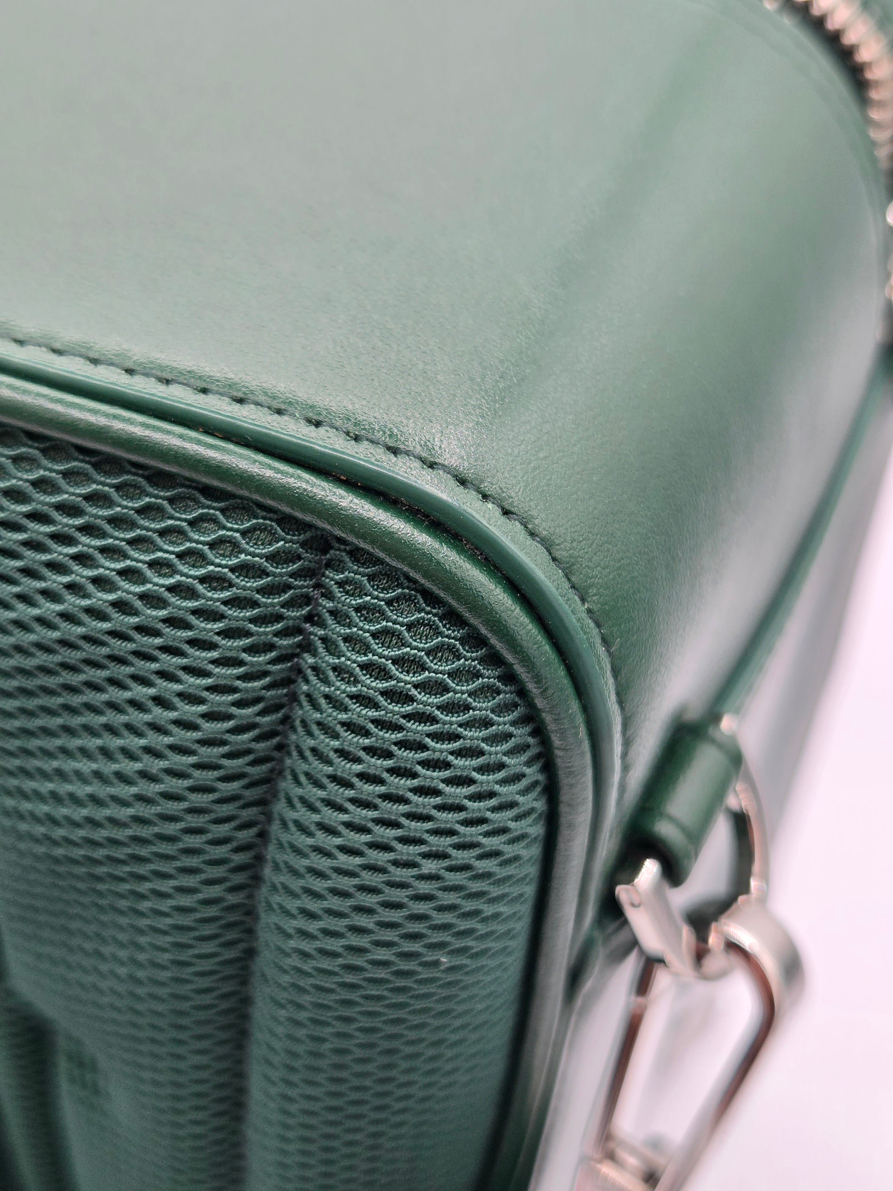 Close-up of a green leather bag with a silver zipper.