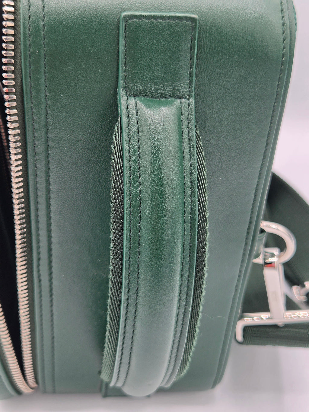 Close-up of a green leather bag with zippers on a white background