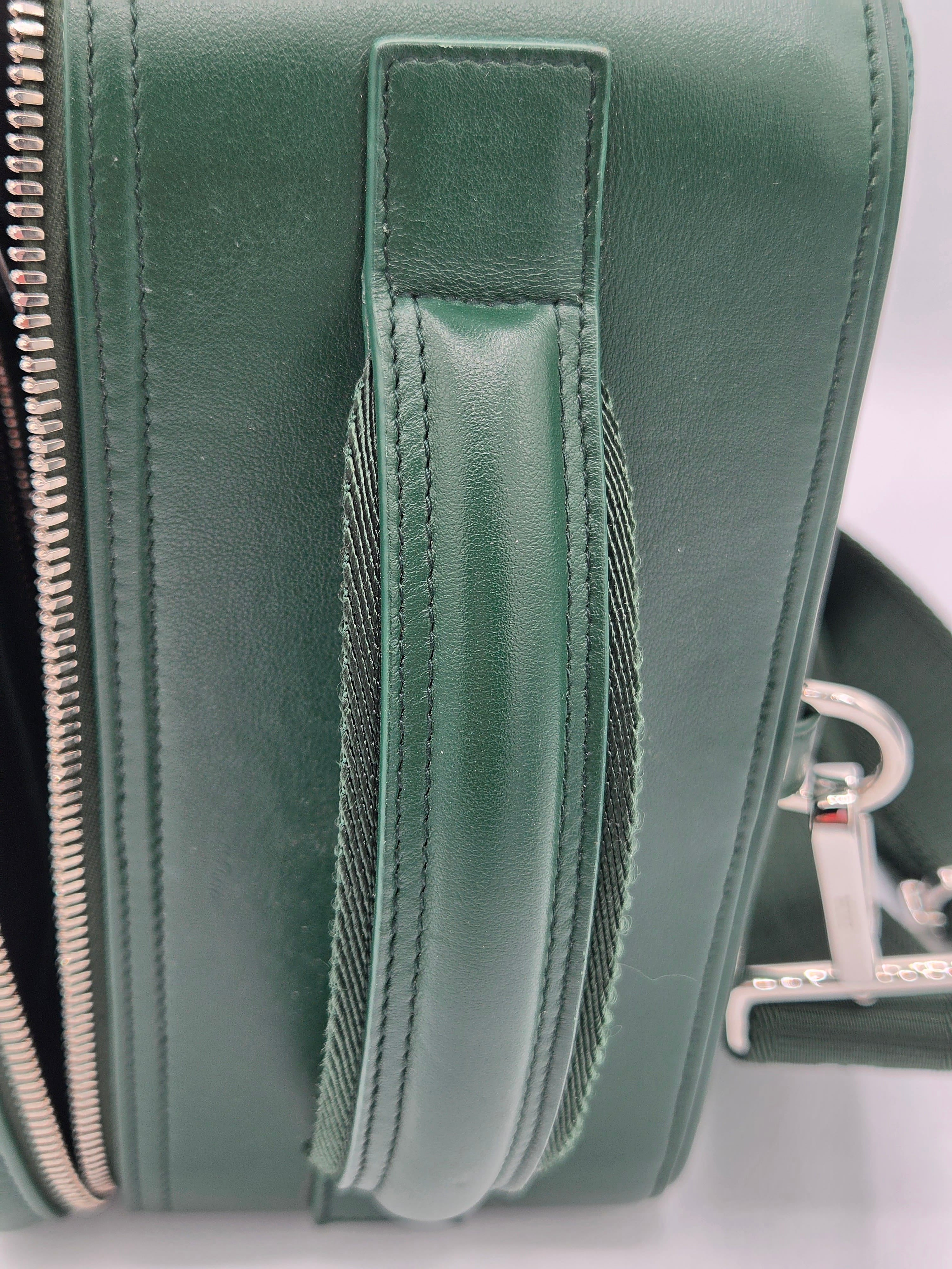 Close-up of a green leather bag with zippers on a white background