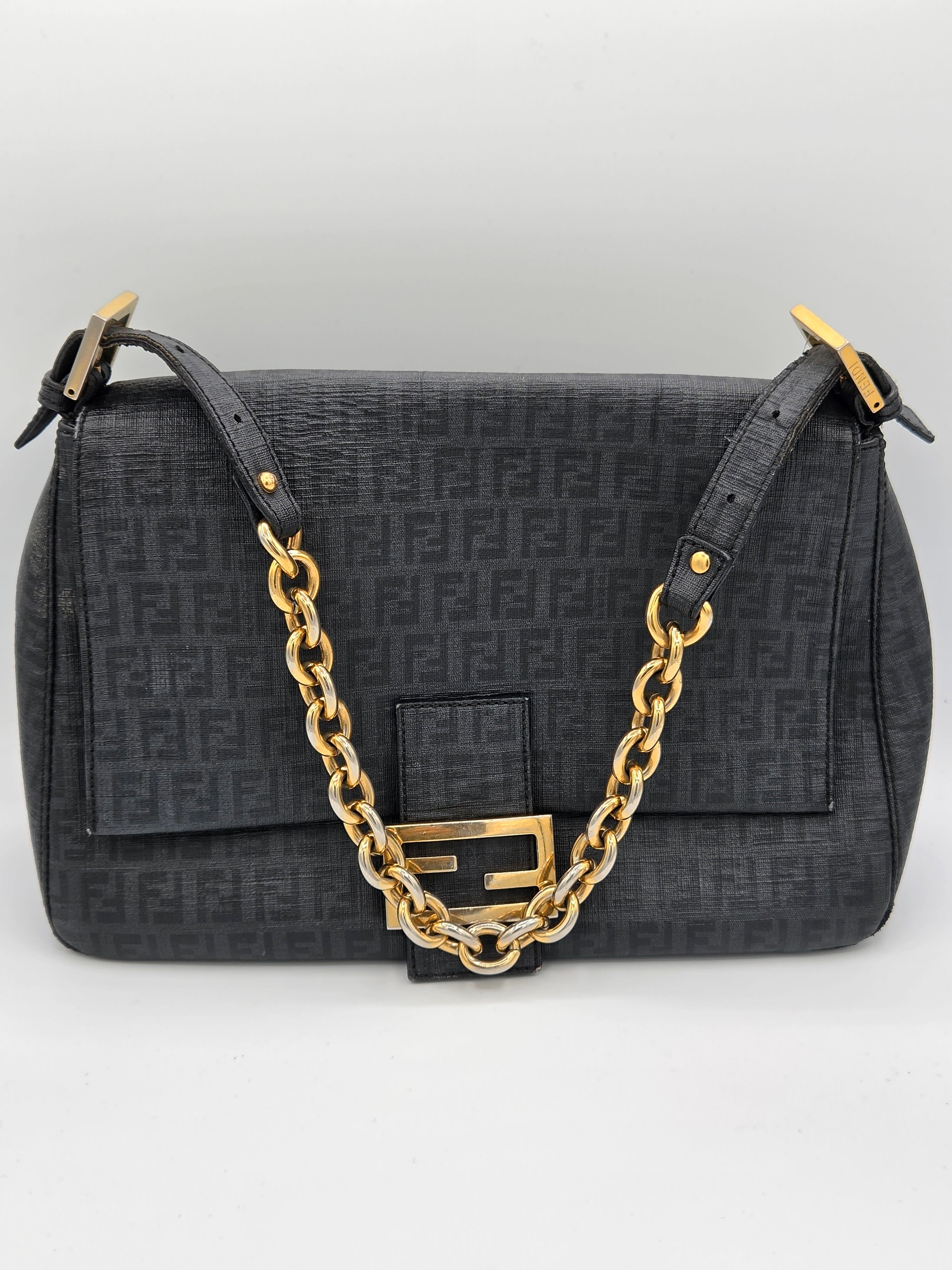Black handbag with gold chain strap on a light gray background