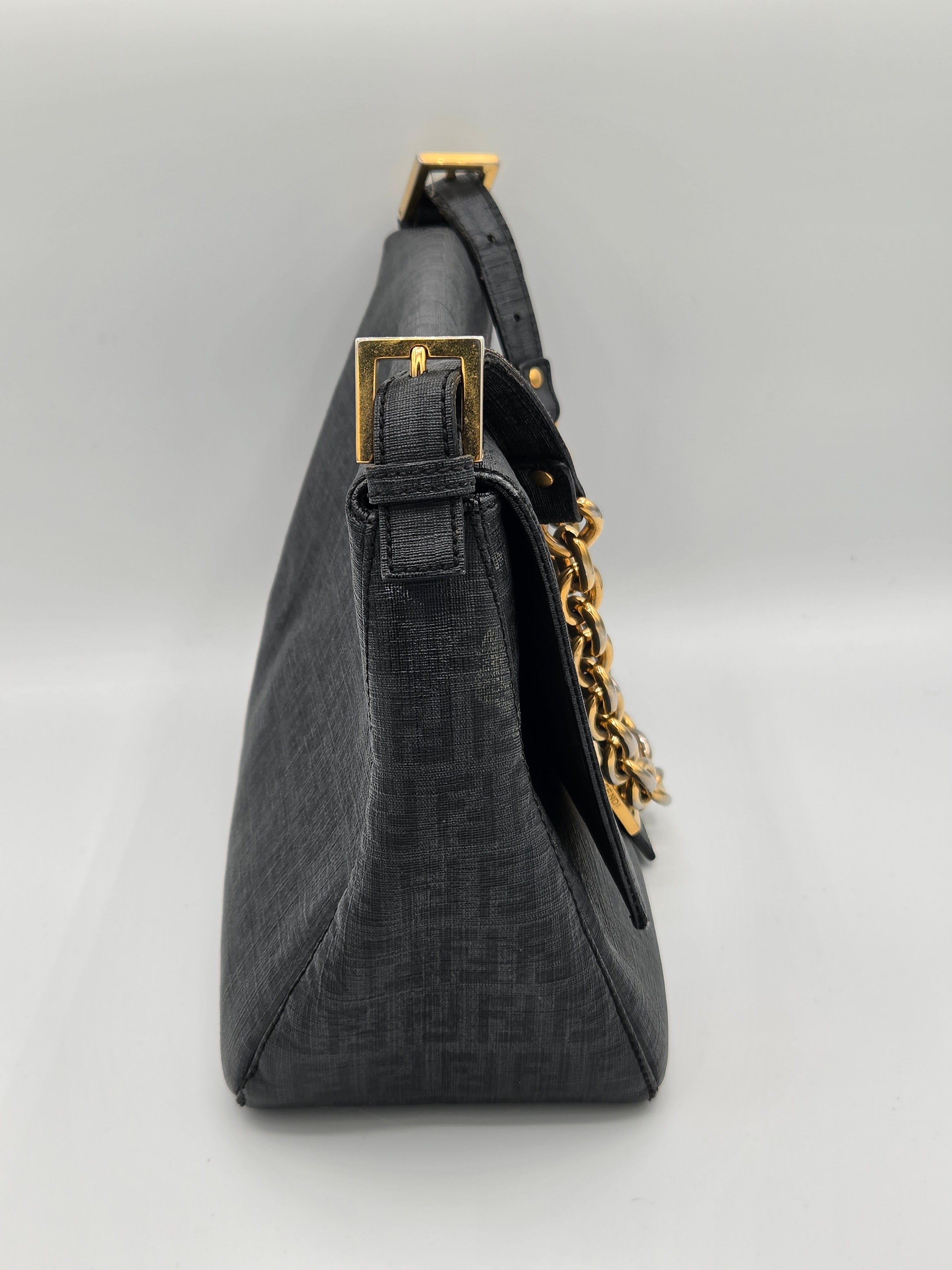 Black handbag with gold chain and buckle on a light gray background