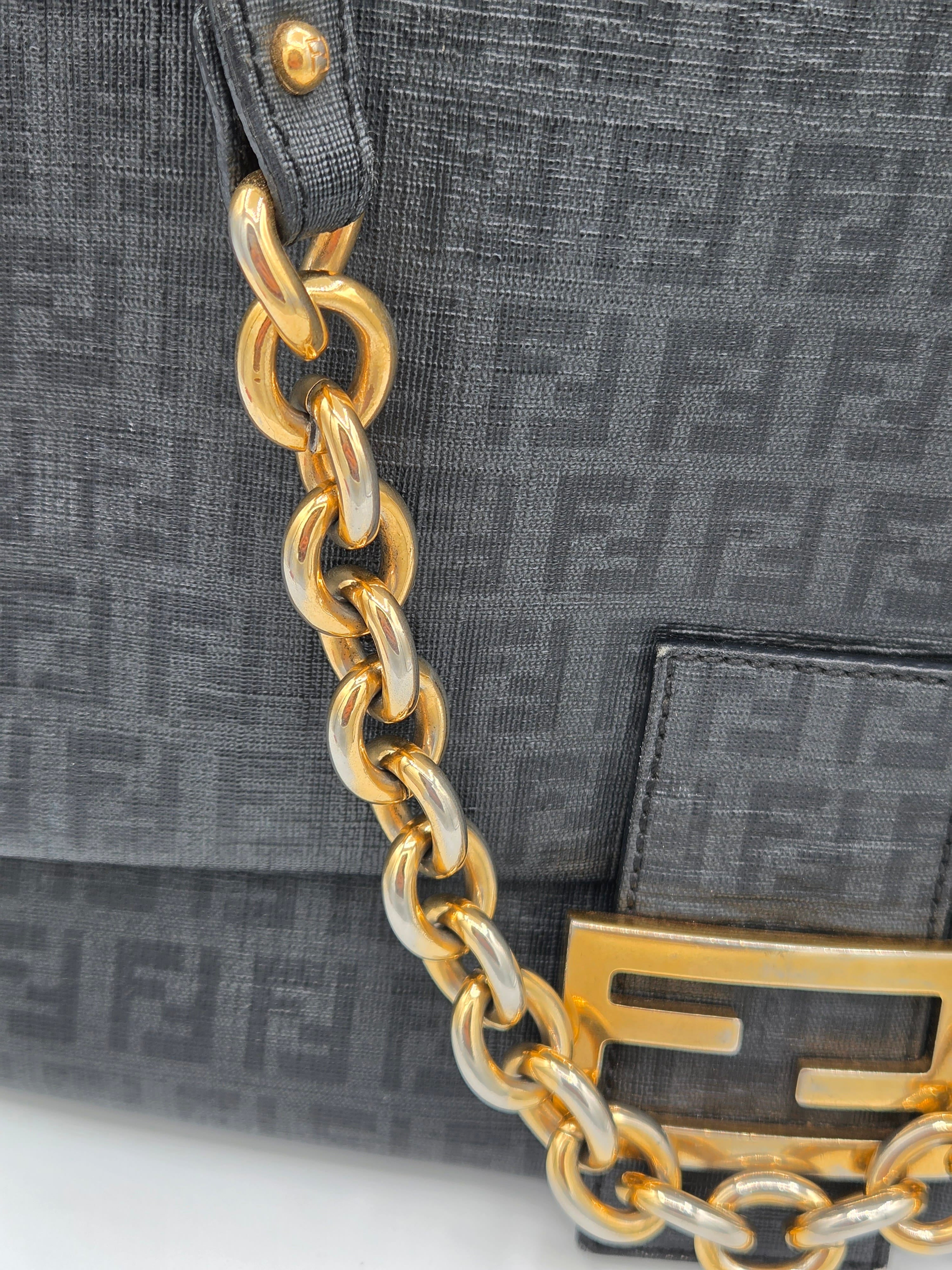 Black handbag with gold chain detail featuring a brand logo.