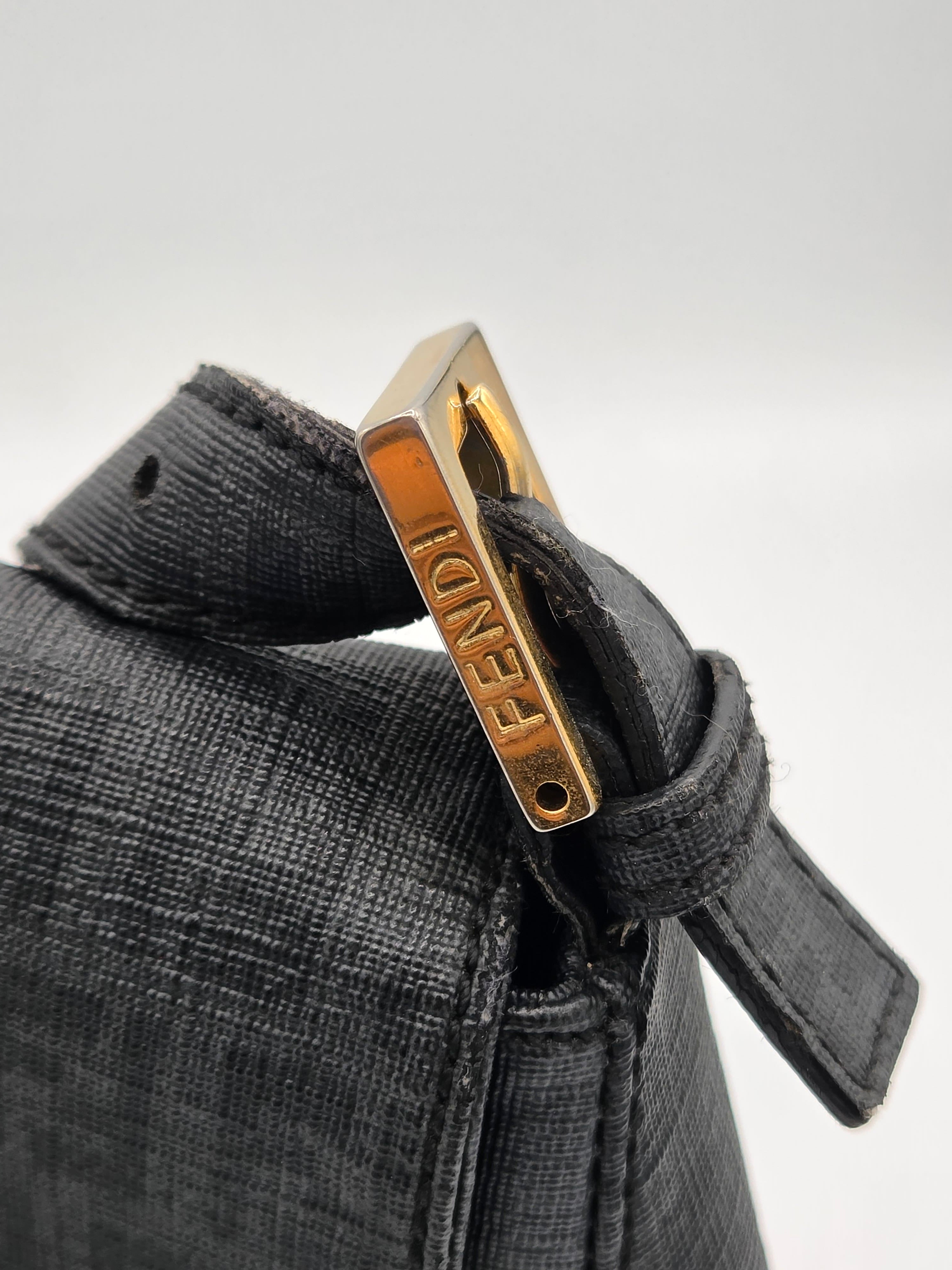 Close-up of a black leather strap with gold hardware on a gray background