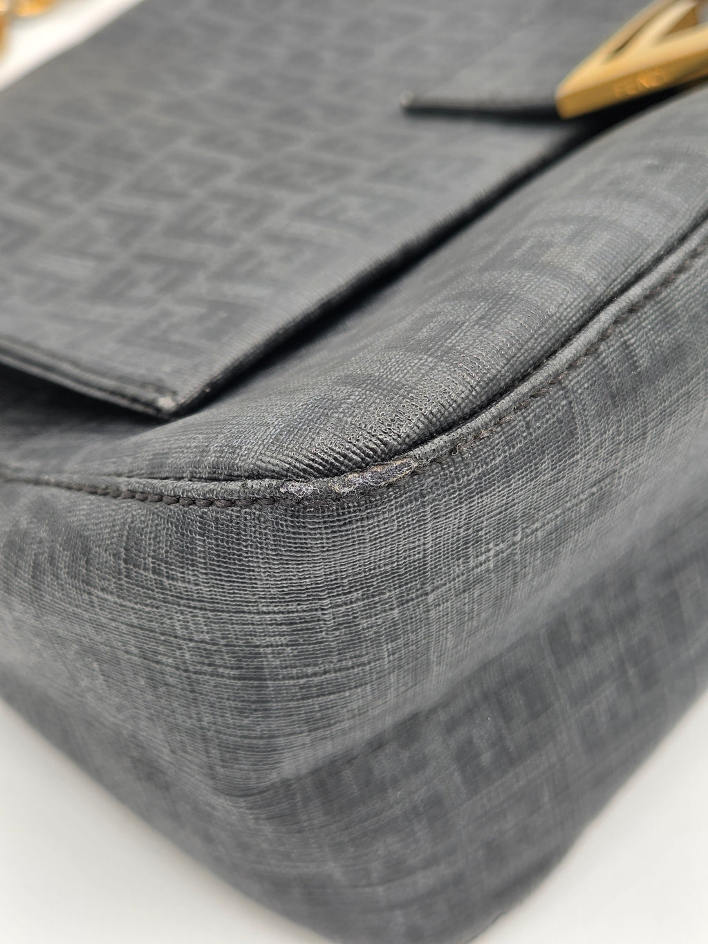 Close-up of a textured gray bag with a gold clasp on a white background