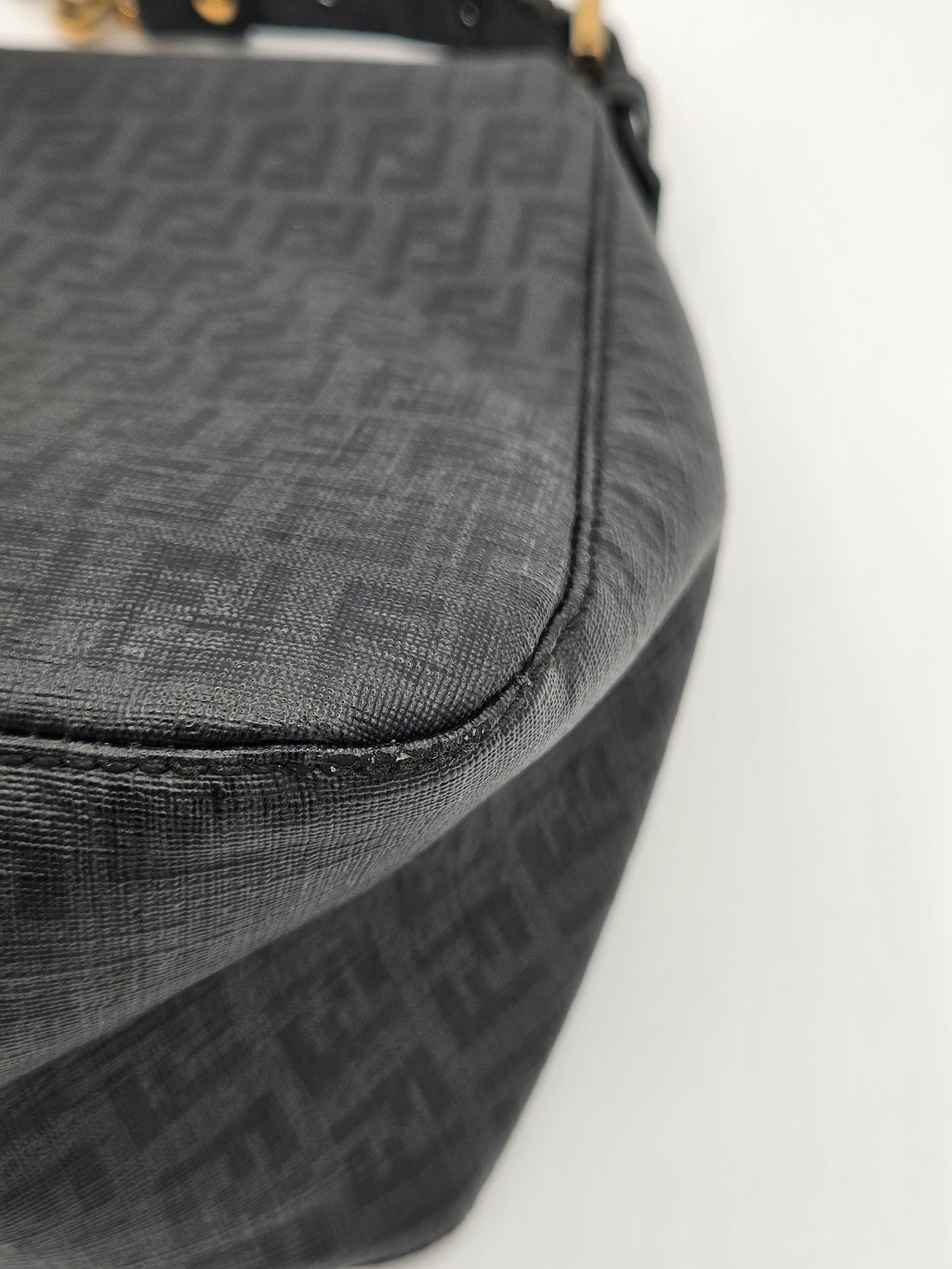 Close-up of a black textured bag with a brand logo on a light gray background