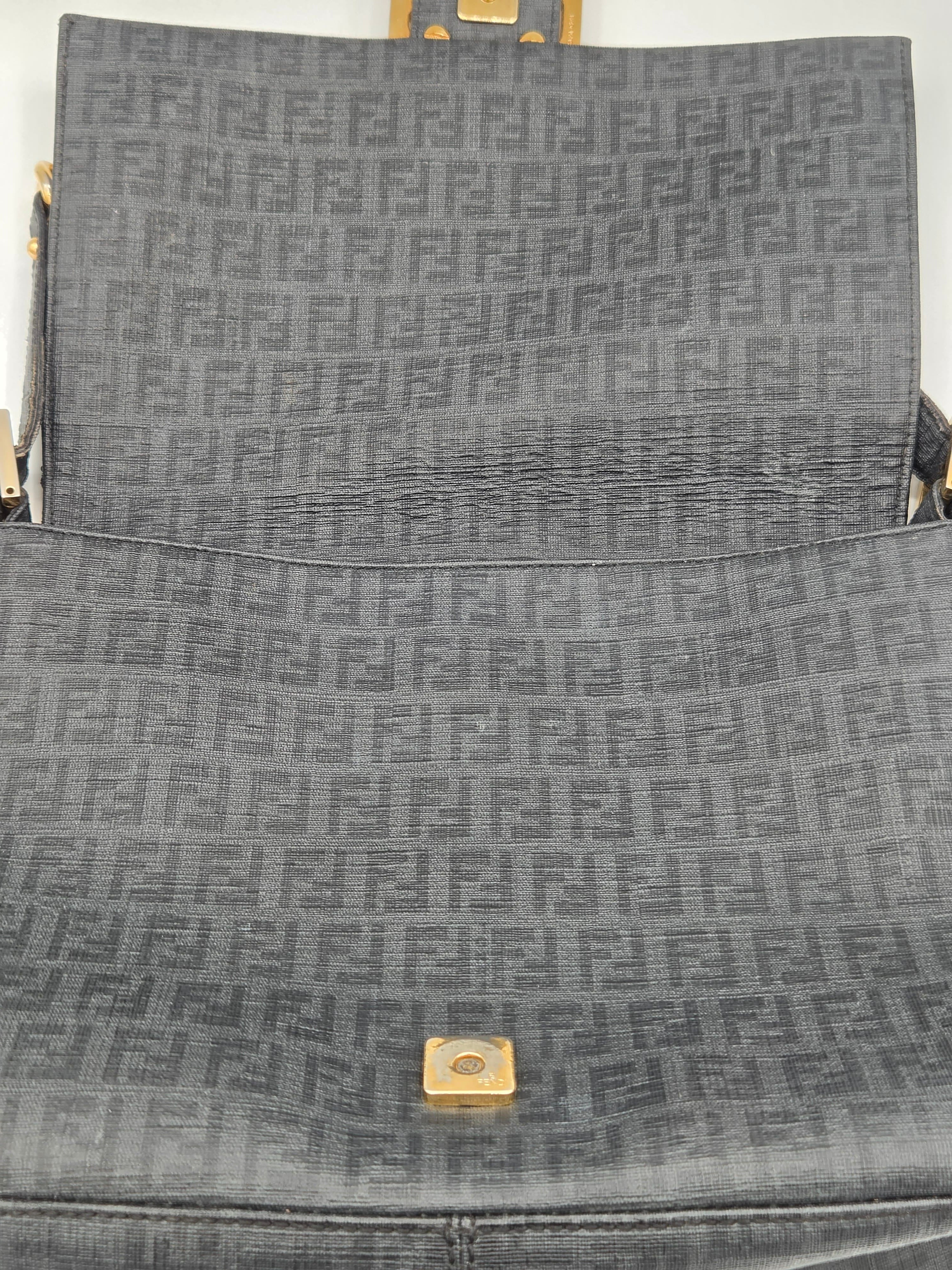 Close-up of a gray textured bag with a gold square emblem.