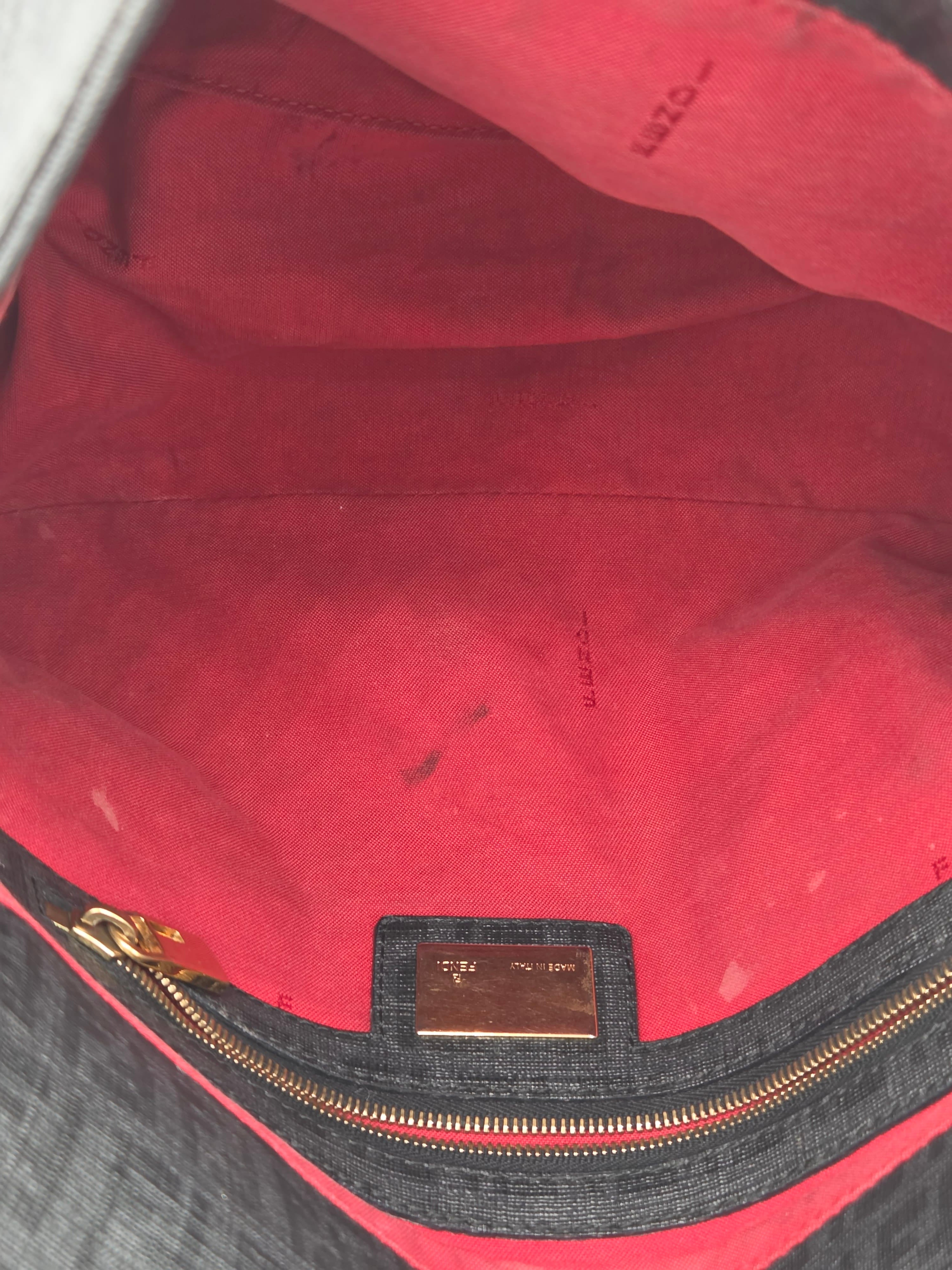 Close-up of a red bag with a gold zipper and brand logo.