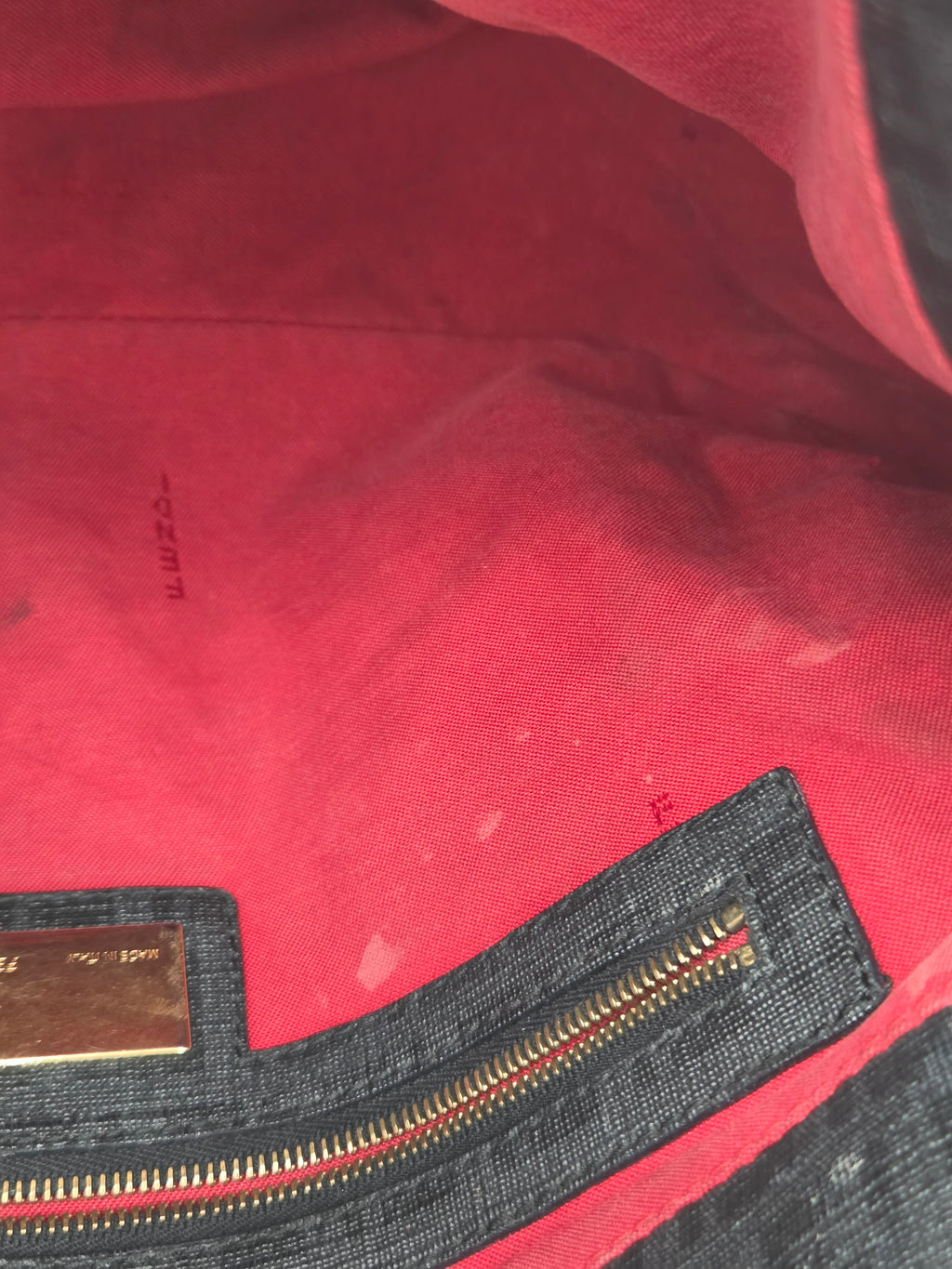 Close-up of a red garment with a zipper and visible brand label.
