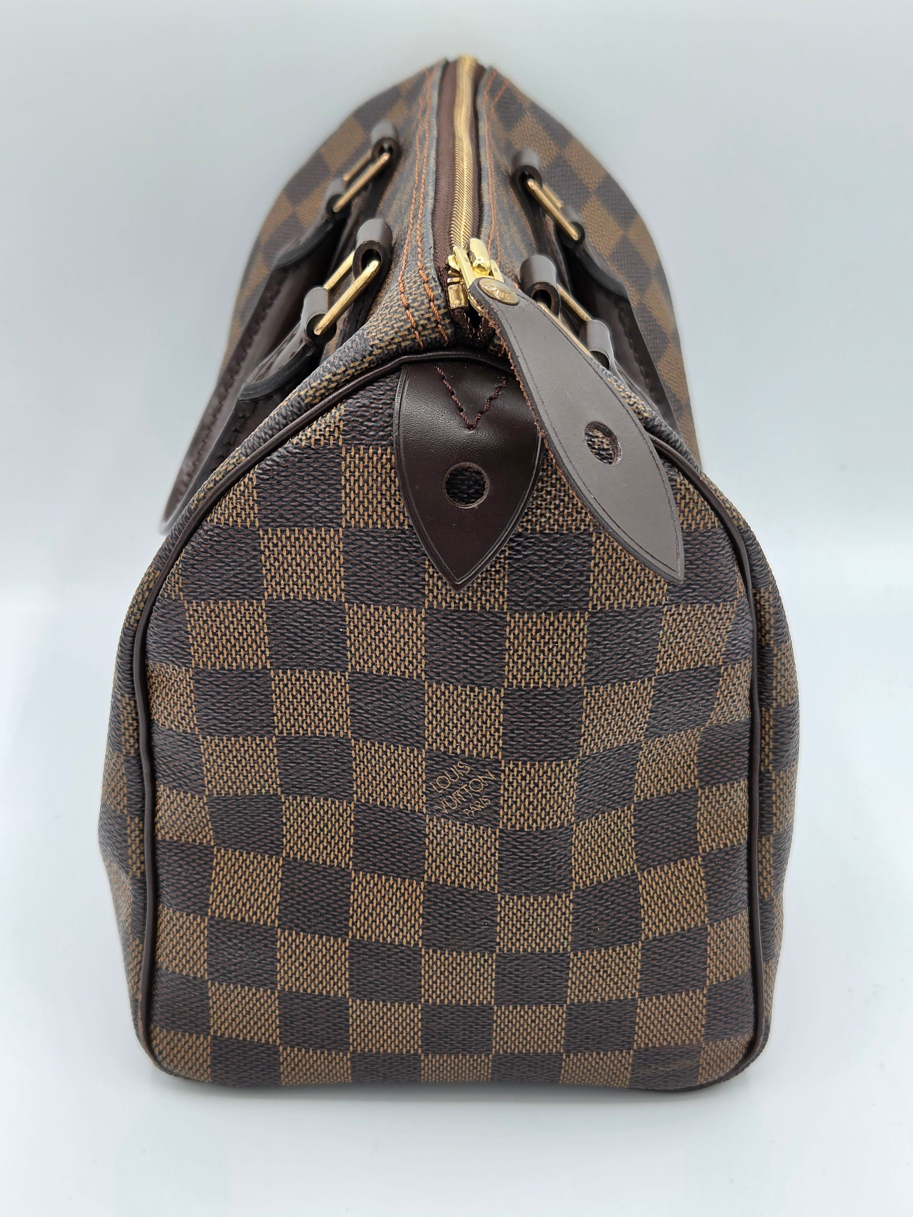 Brown checkered handbag with gold accents on a light gray background