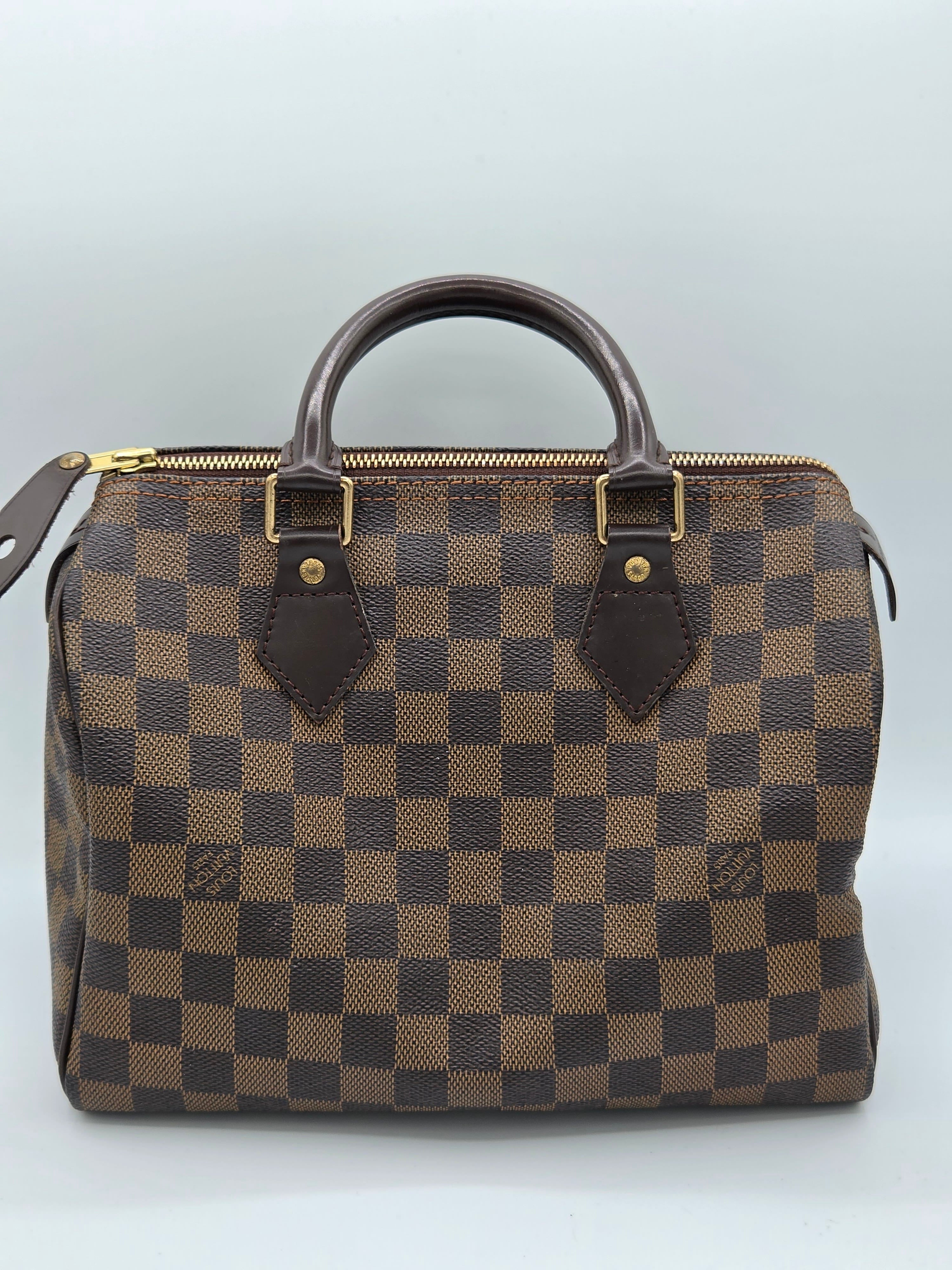 Brown checkered handbag with brown handle on a light gray background