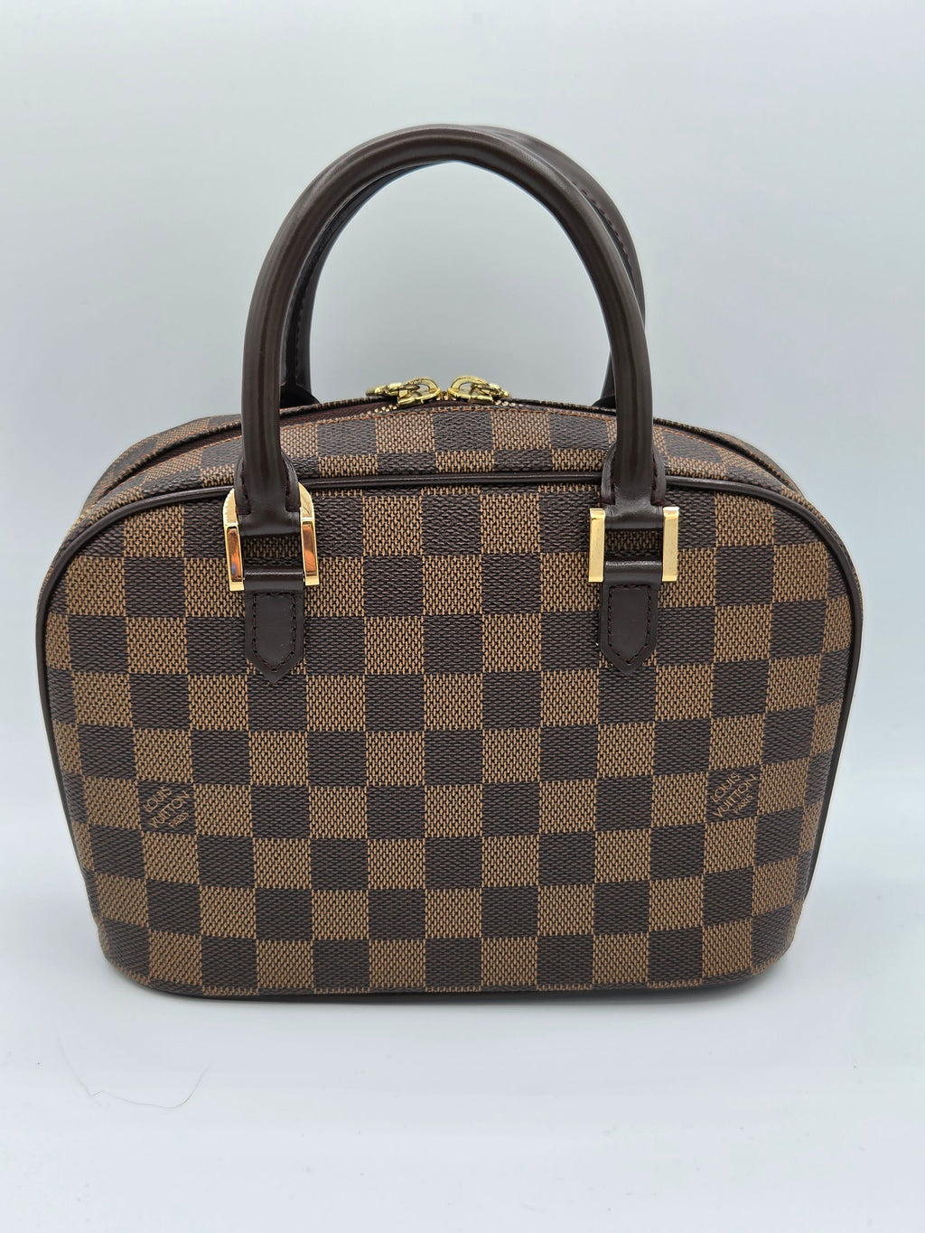 Brown checkered handbag with gold accents on a light gray background