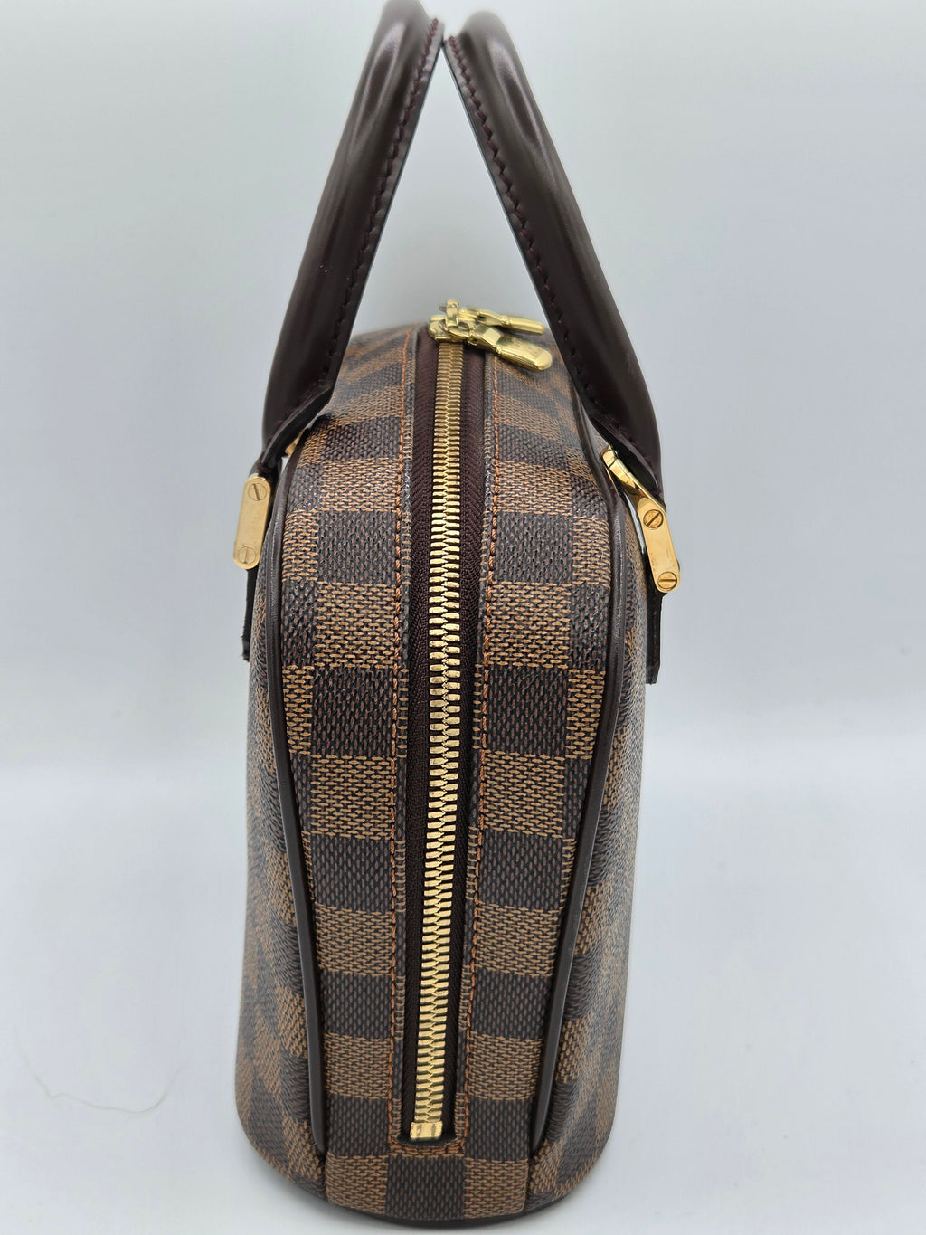 Brown checkered handbag with gold zippers on a light gray background