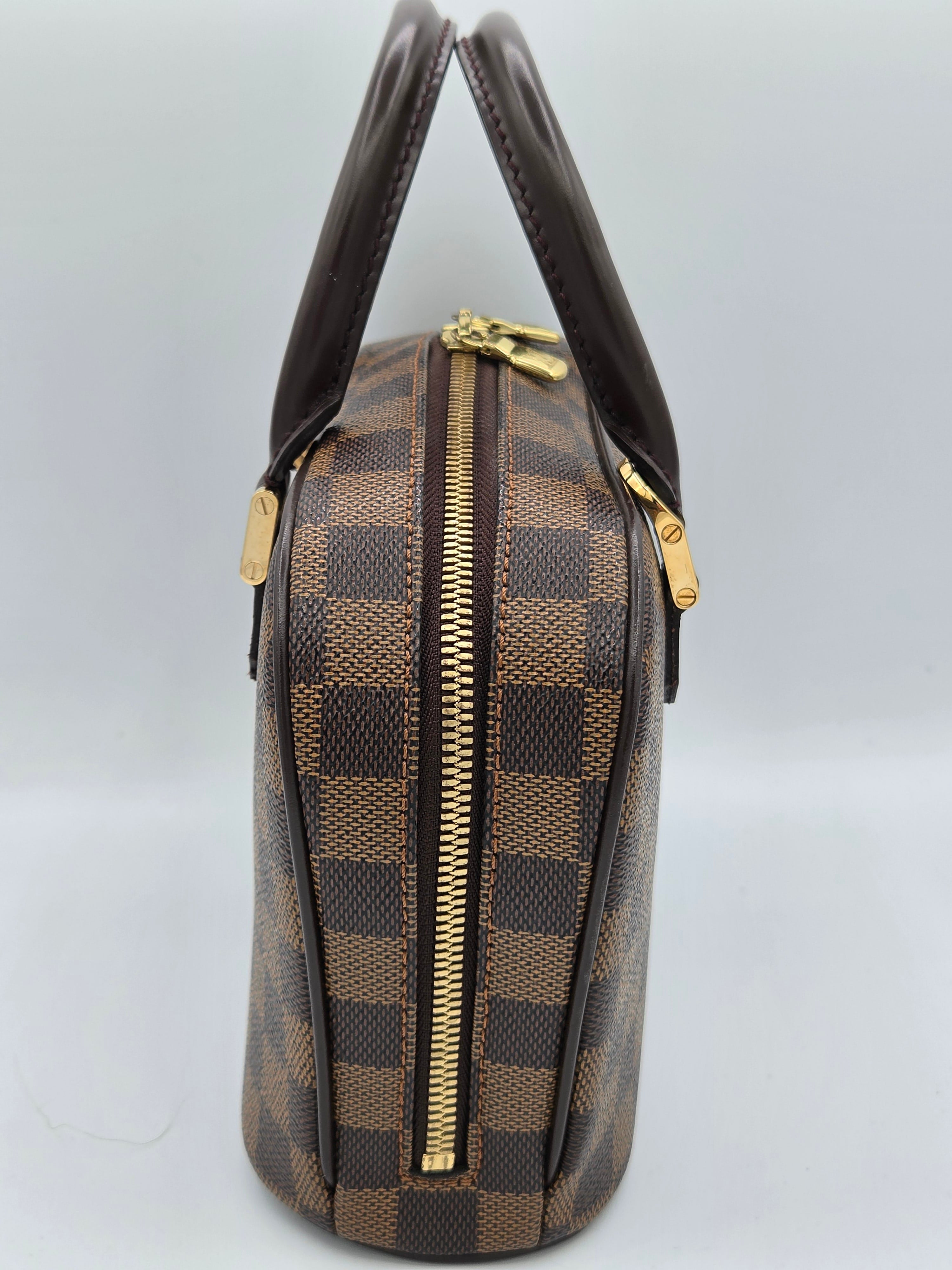Brown checkered handbag with gold zippers on a light gray background