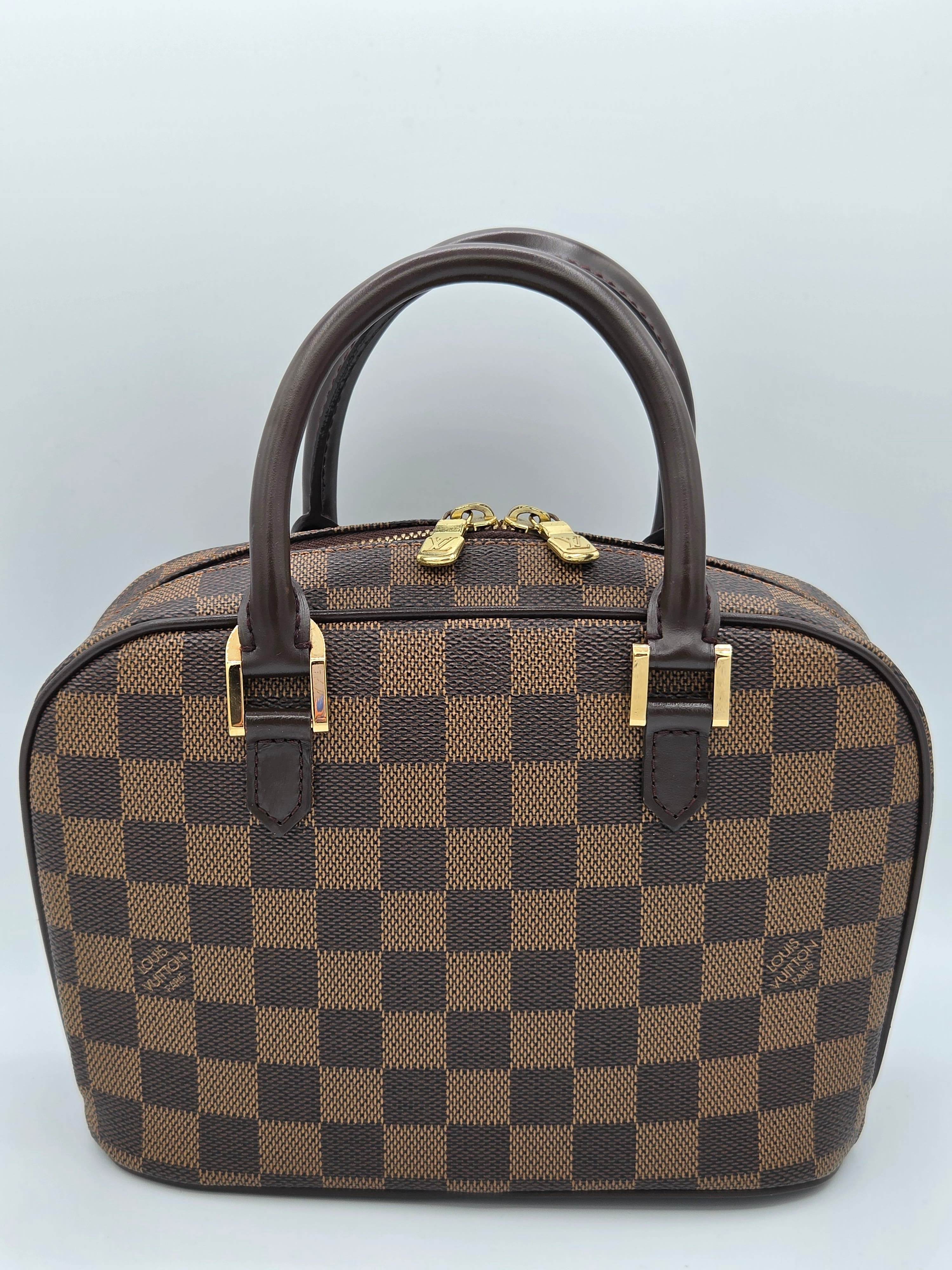 Brown checkered handbag with gold accents on a light gray background