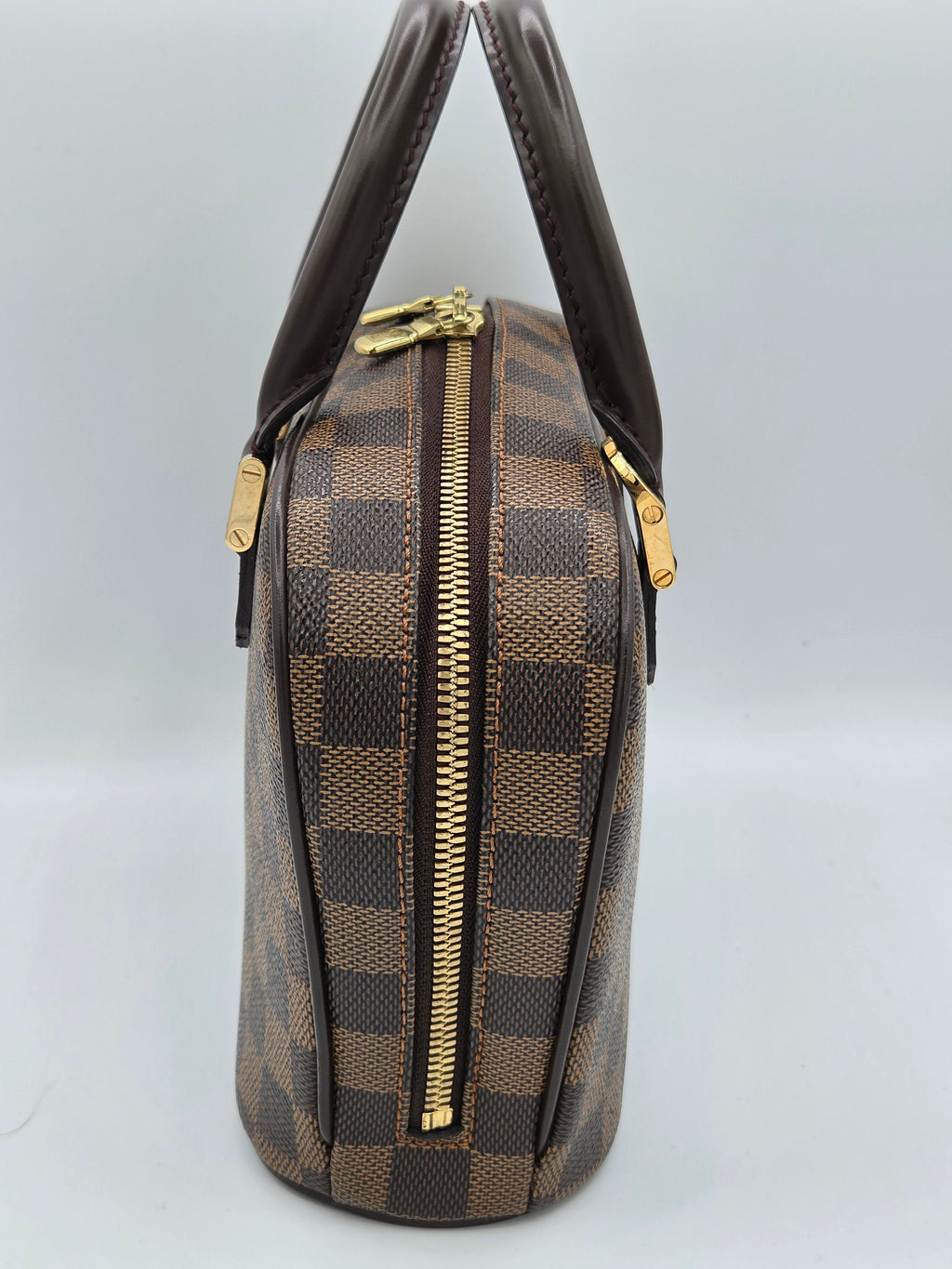 Designer handbag with brown and gold checkered pattern on a light gray background
