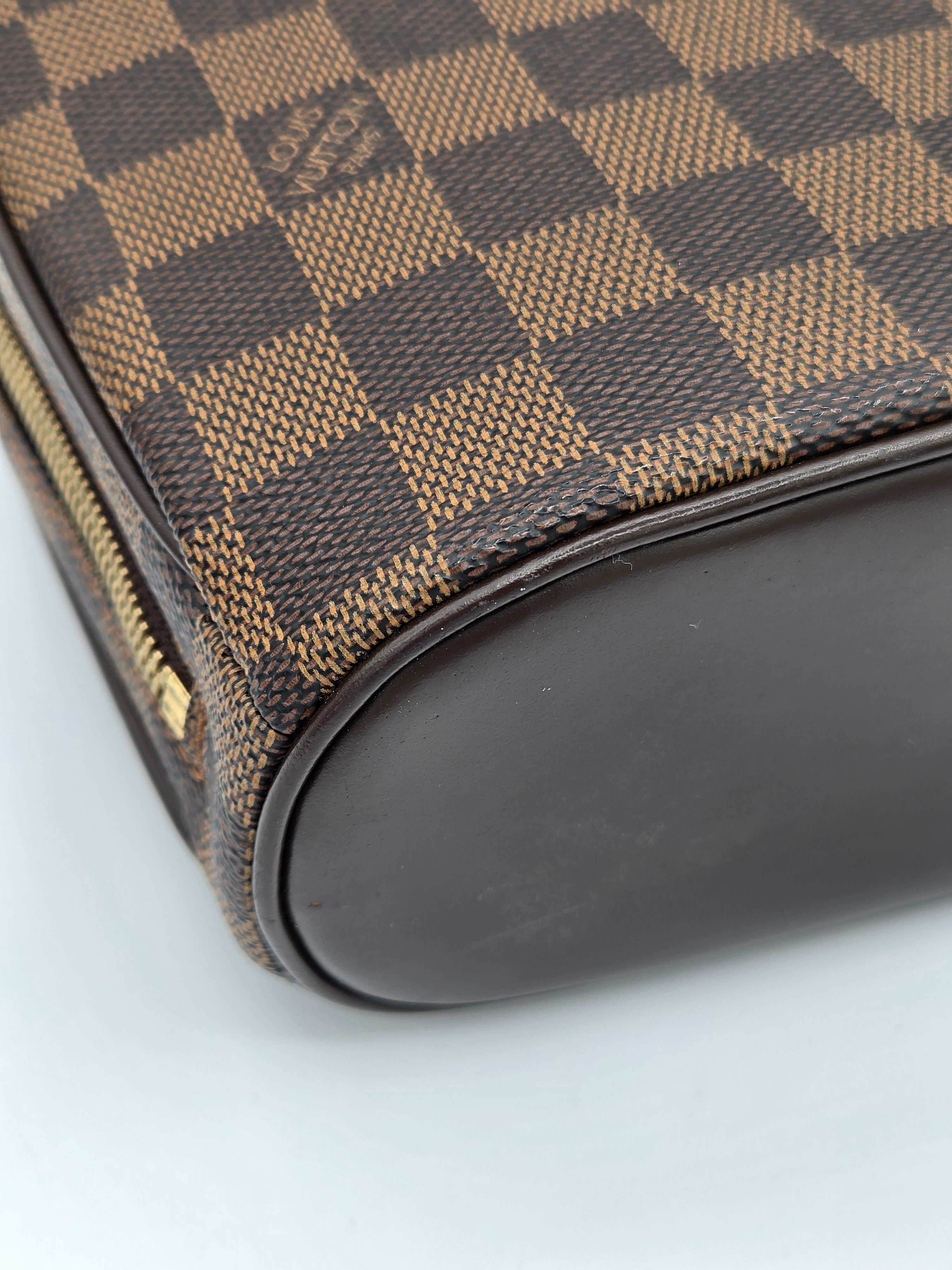 Close-up of a brown checkered bag with a black strap on a light gray background