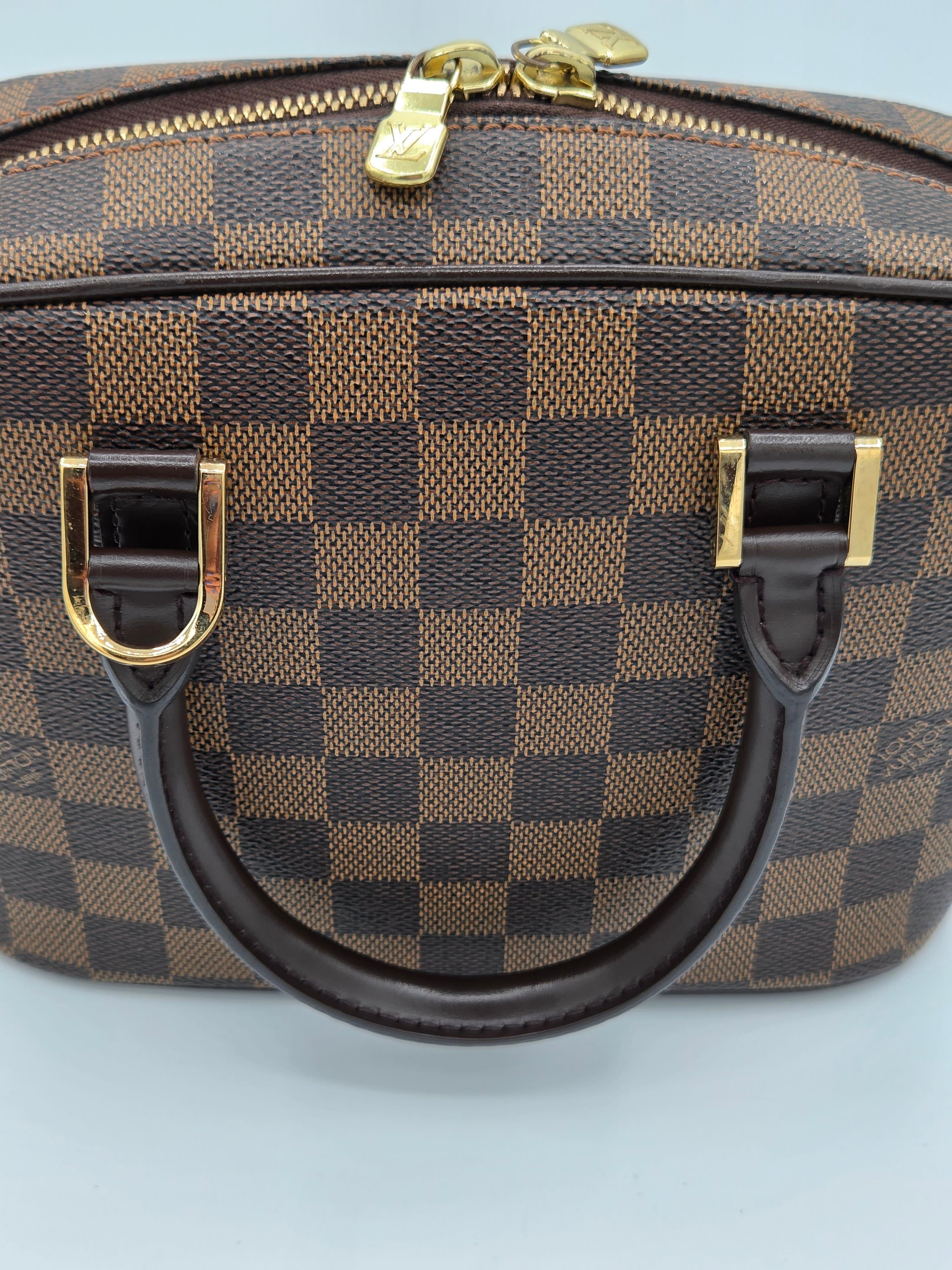 Brown checkered handbag with gold accents on a light gray background