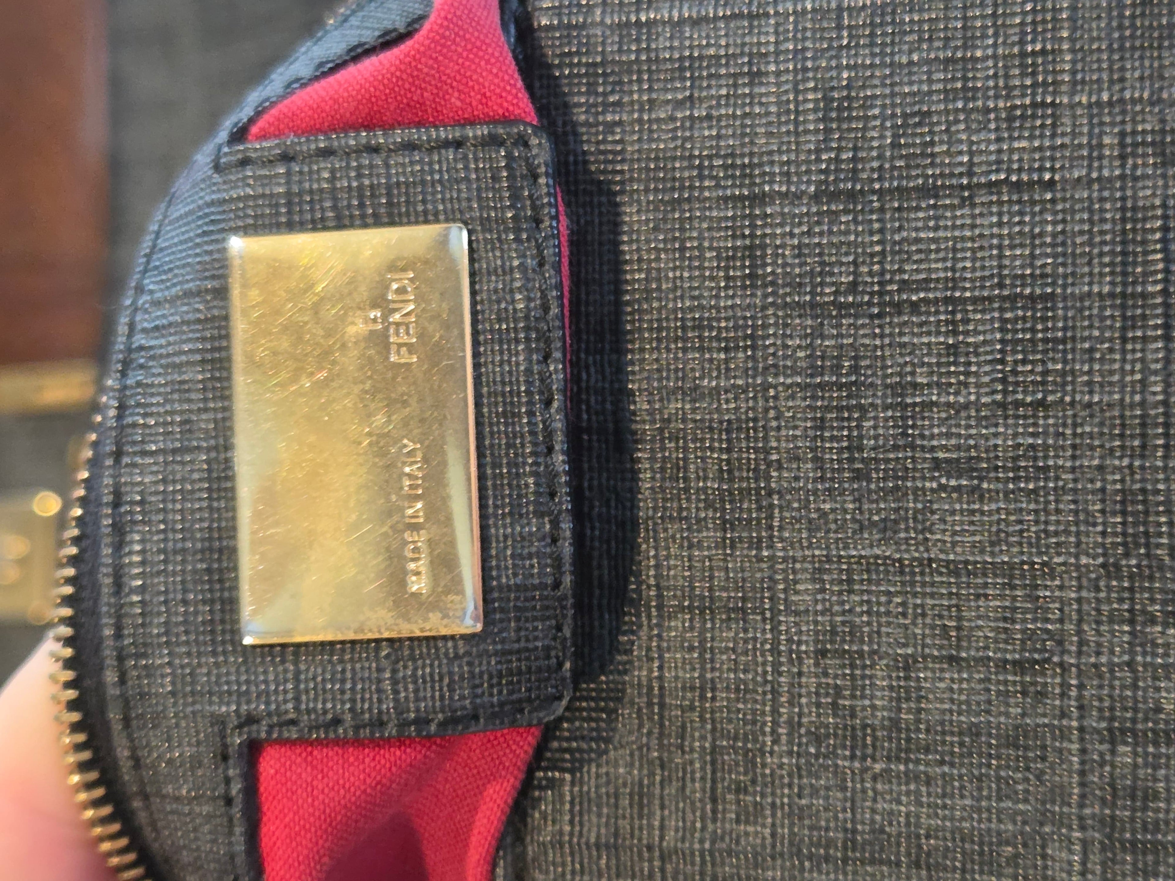 Close-up of a Fendi wallet with a gold tag on a textured surface.