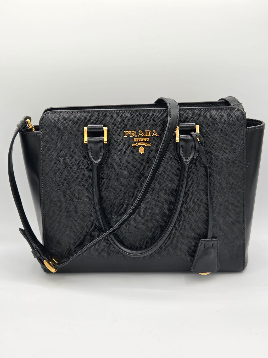 Black Prada handbag with gold accents on a white background