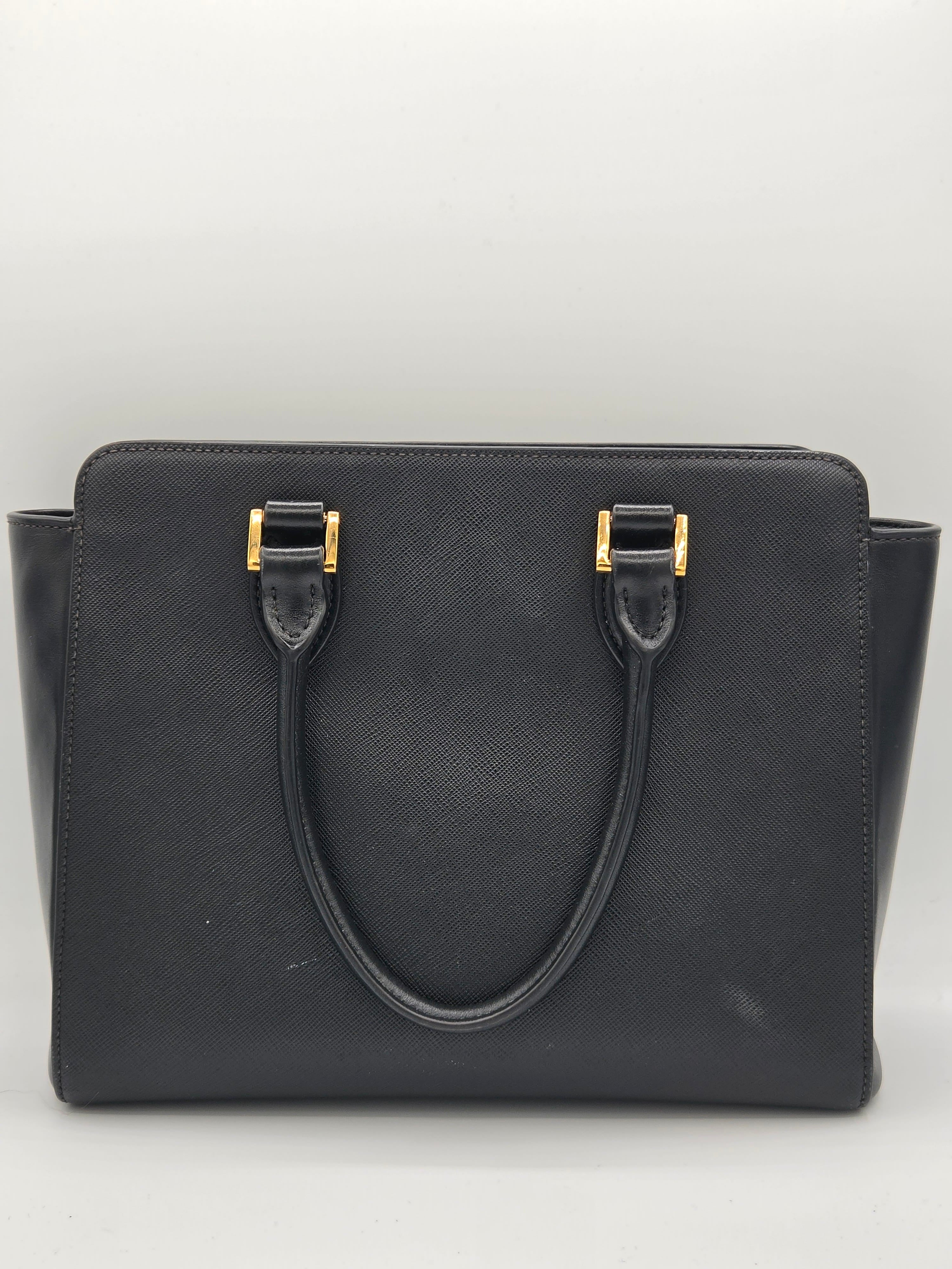 Black handbag with gold hardware on a light gray background