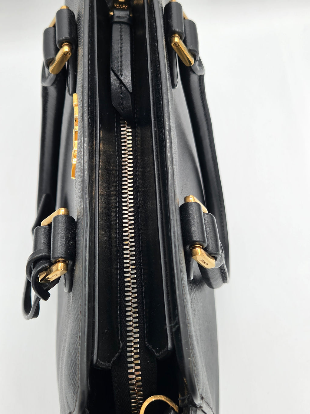 Black handbag with gold accents on a light gray background