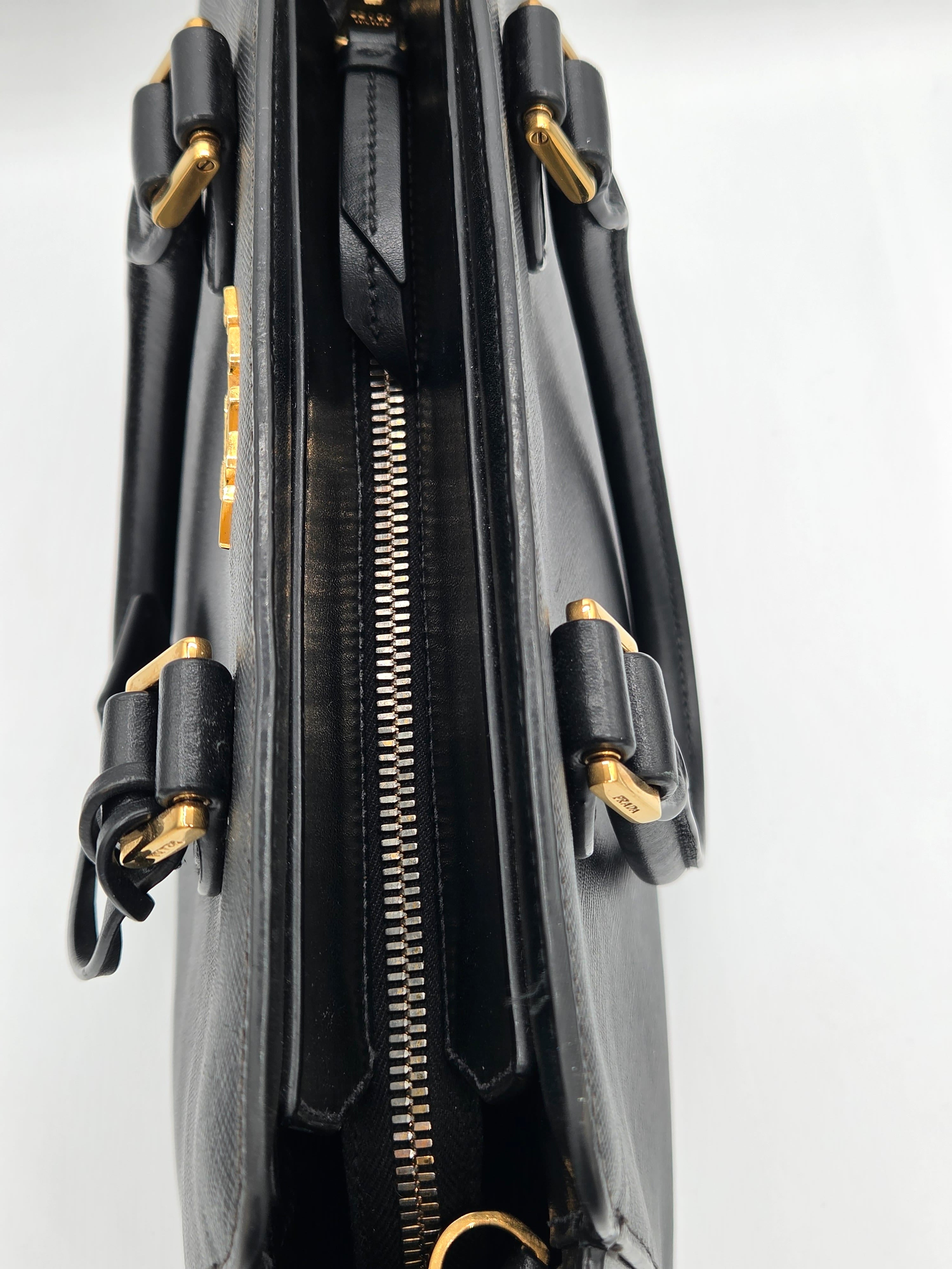 Black handbag with gold accents on a light gray background