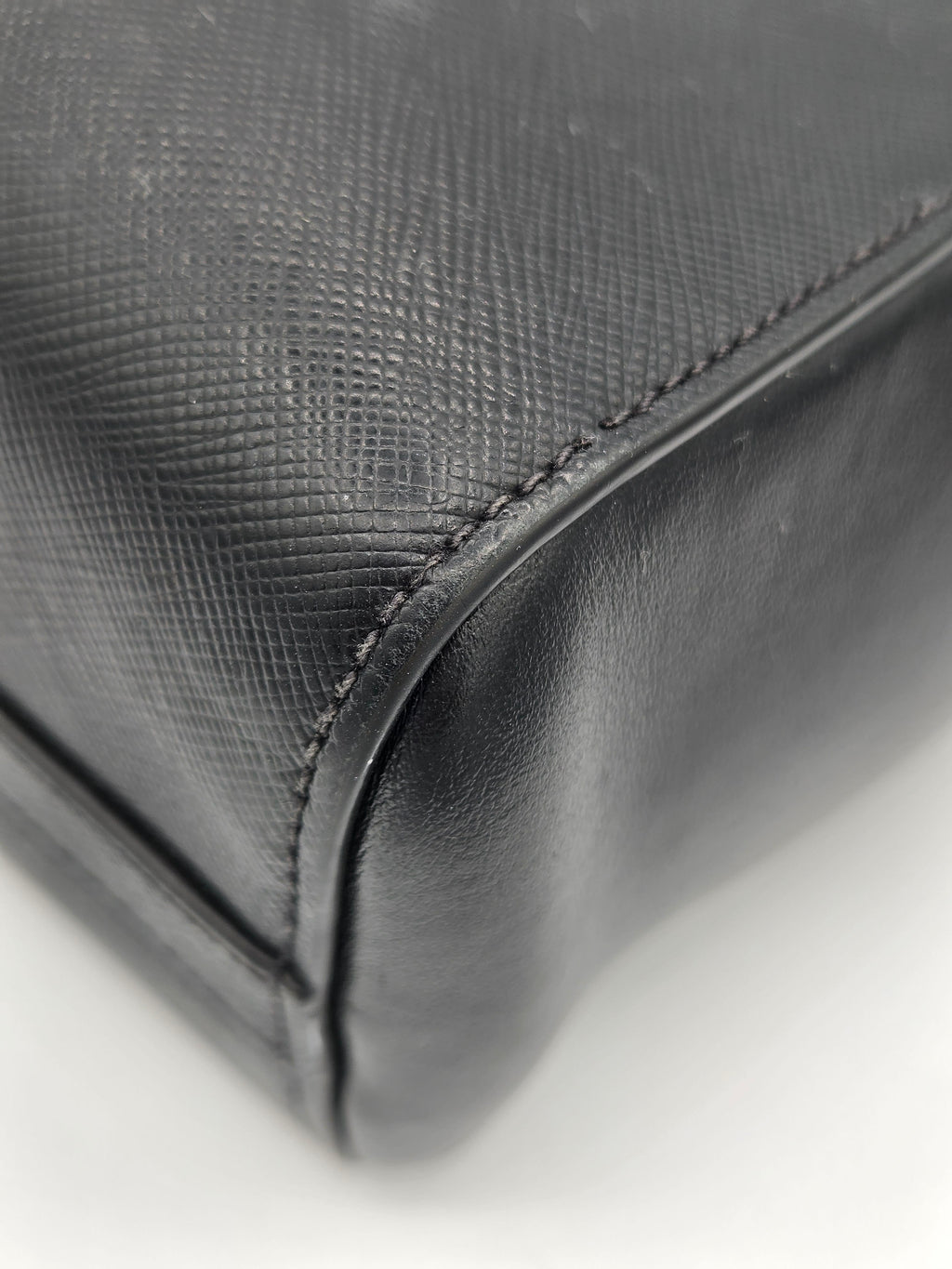 Close-up of a textured black bag corner on a white background