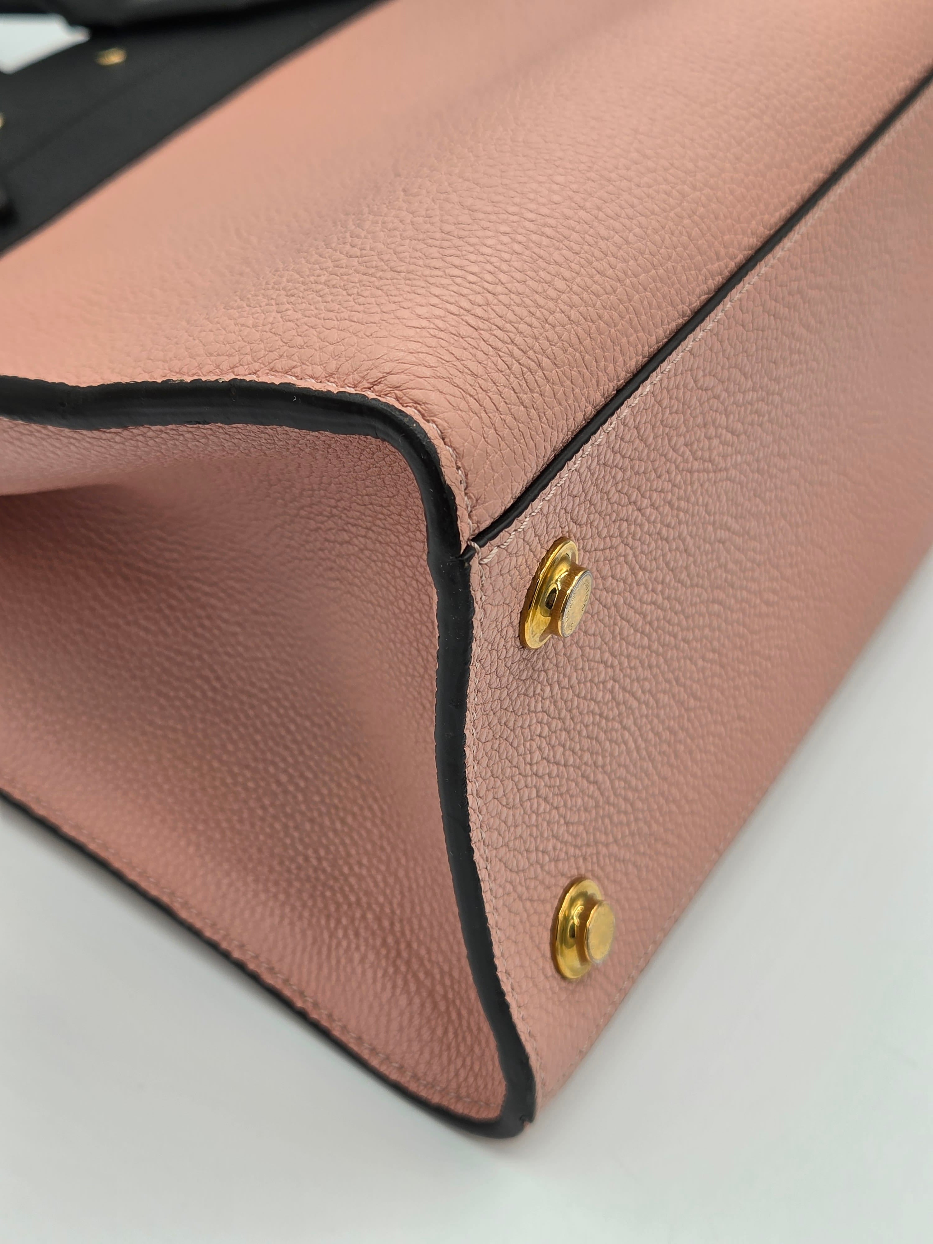 Close-up of a pink leather handbag with gold studs on a light gray background