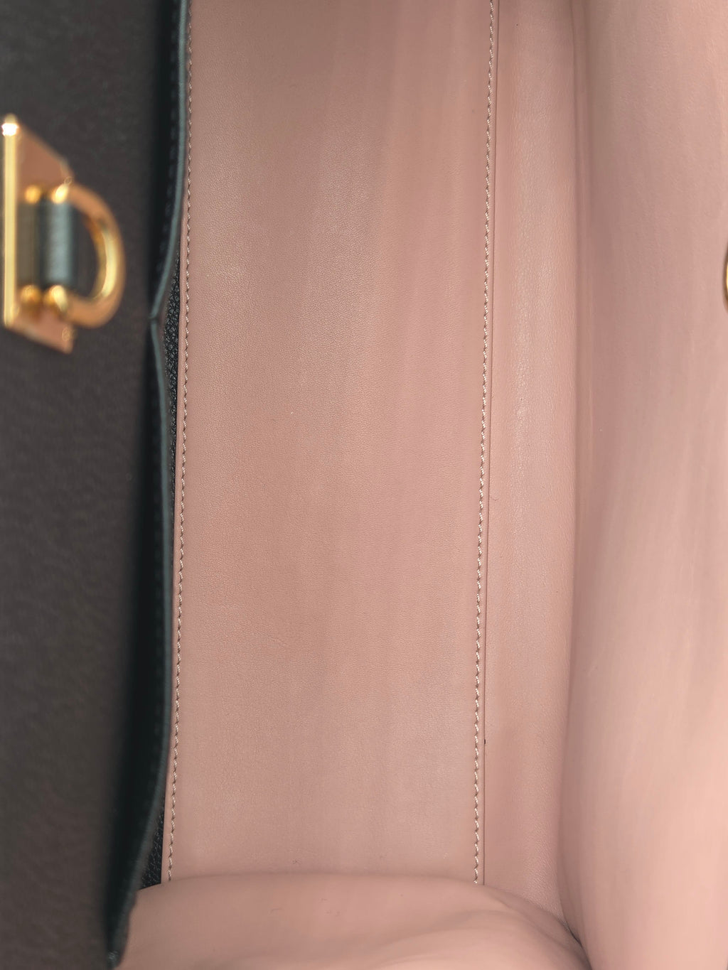 Close-up of a handbag with a gold clasp on a black background