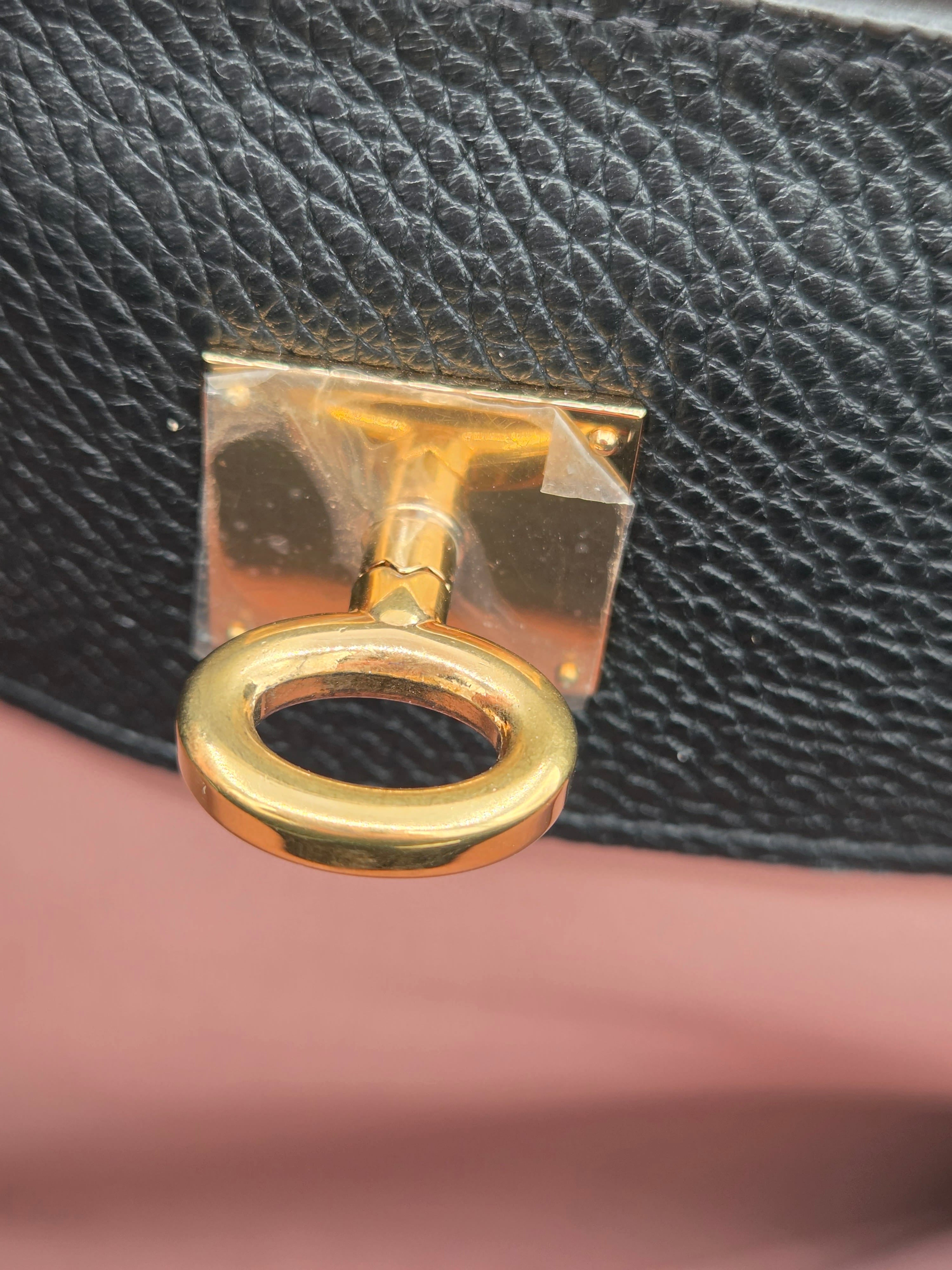 Close-up of a gold key-shaped clasp on a black leather surface