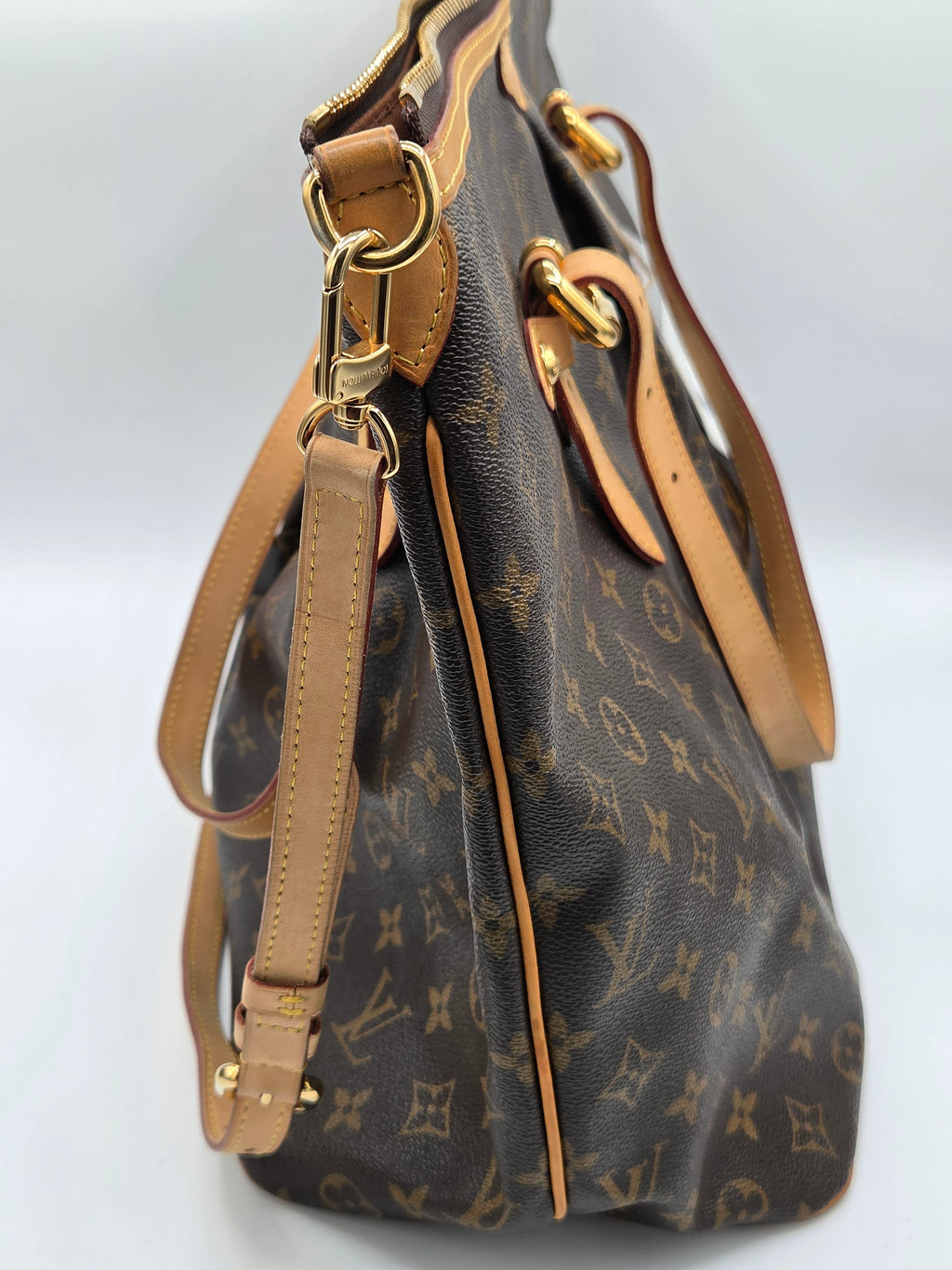Designer handbag with monogram pattern on a light gray background